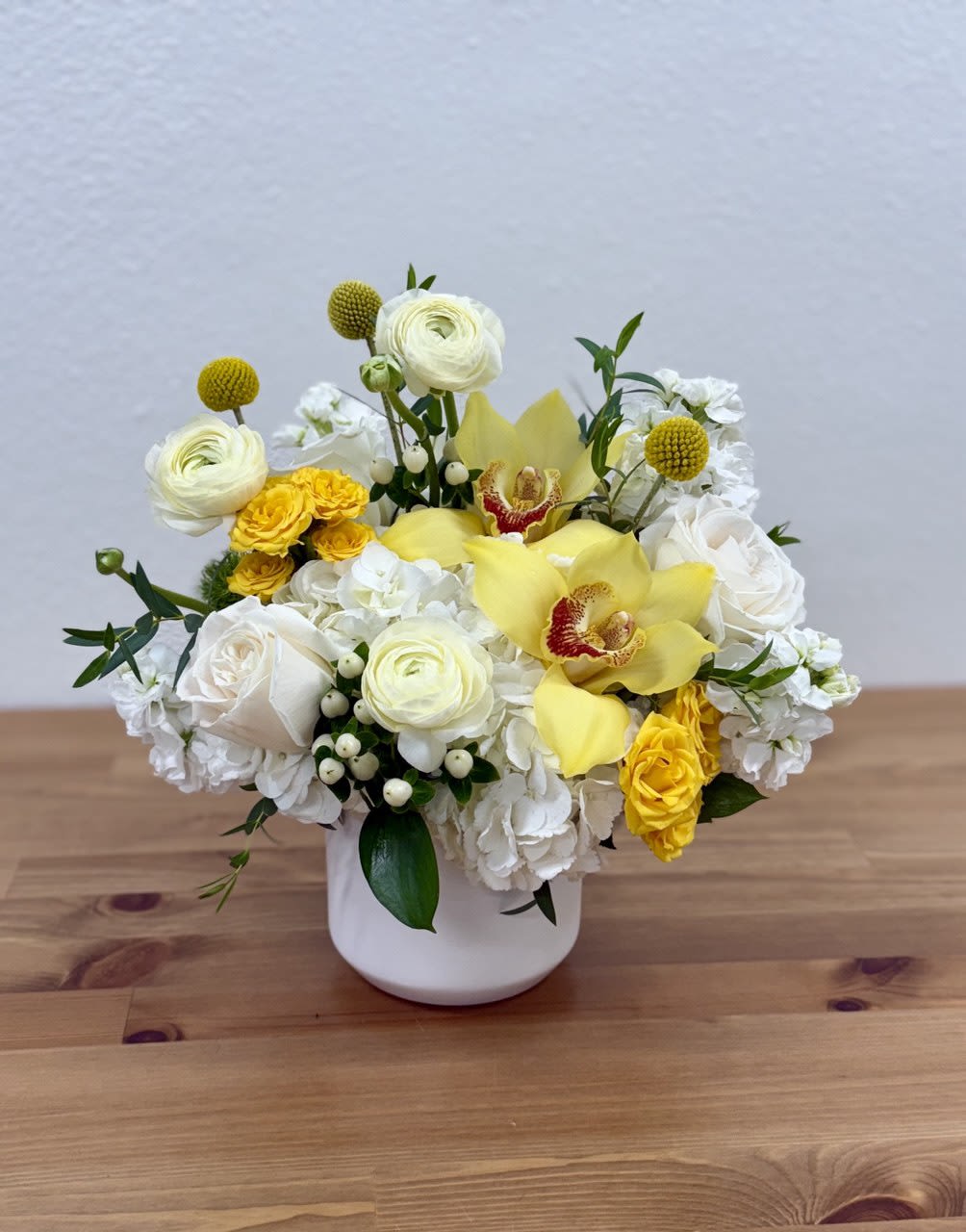 White and yellow floral arrangement in a white vase
