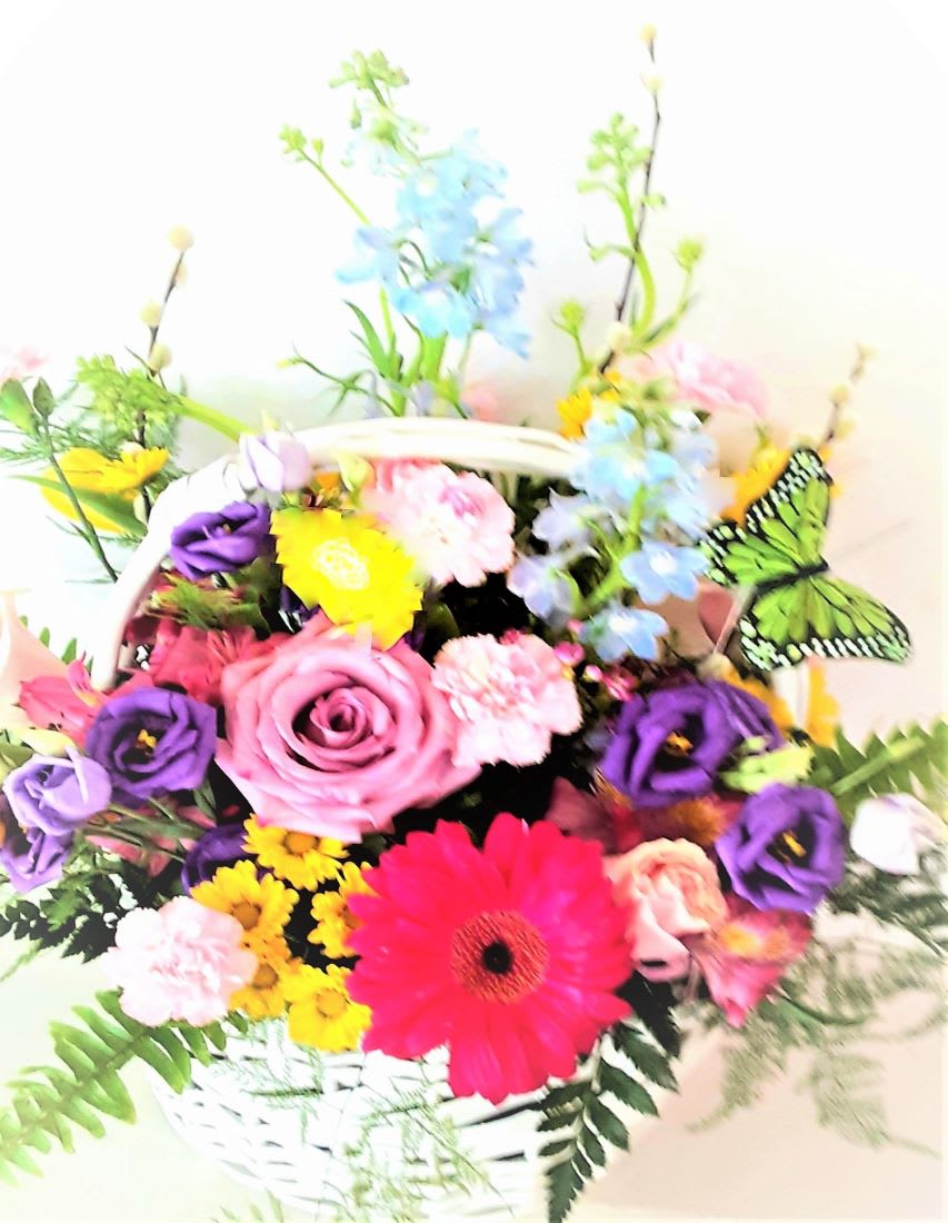 Colorful mixed flower arrangement in a white basket with a pink gerbera daisy