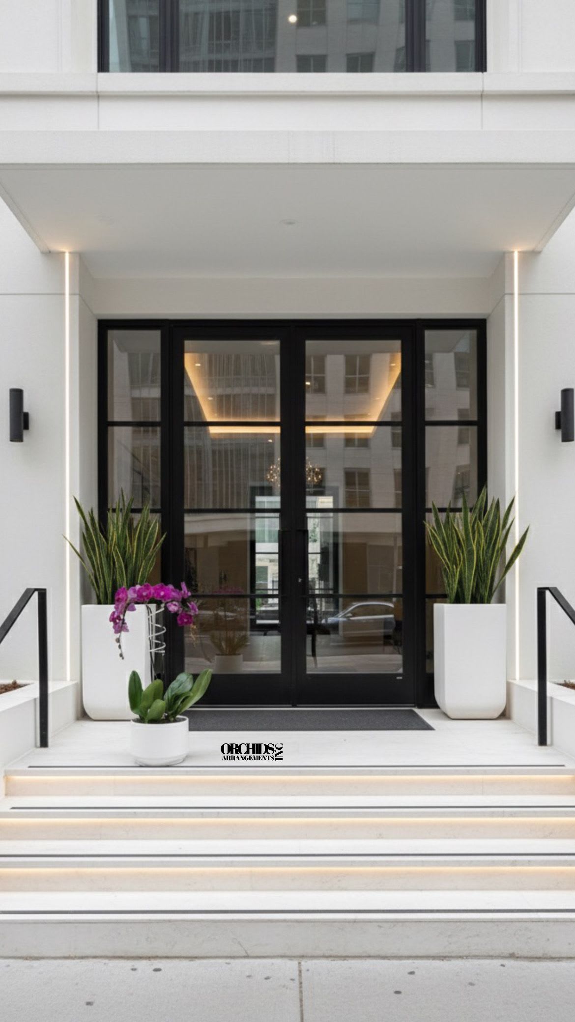 Orchid arrangement in white planters at a modern building entrance