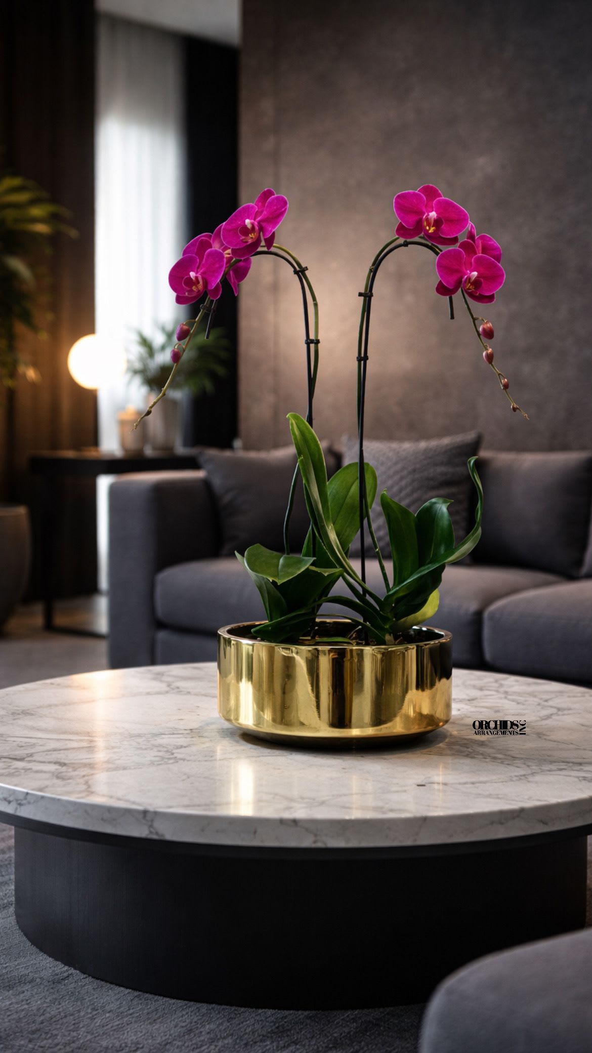 Pink orchids in a gold planter on a marble table