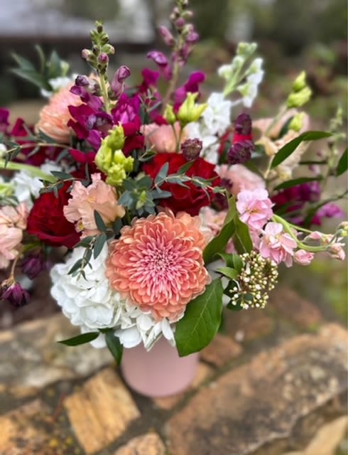 Farmboy Love - Featuring mauvy tones, burgundy, and peach, this dreamy combination is sure to make a statement! Mums, roses, stock, snapdragons, and lisianthus in a tall neutral pastel cylinder.