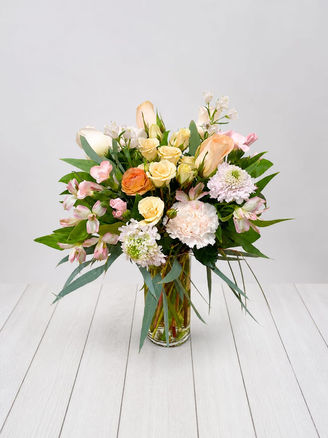 Peach Garden -   Peach Garden Floral Arrangement in Glass Vase  Peach Garden is a soft, romantic peach and blush floral arrangement in a clear glass vase, hand designed by a local East Moline florist with delivery available.  Peach Garden features a refined, garden inspired design with peach roses, spray roses, alstroemeria, and textured seasonal blooms in a balanced, airy composition, with blooms selected at the designer’s discretion based on seasonal availability.  Peach Garden is available for delivery in East Moline, Moline, Rock Island, Silvis, Davenport, and Bettendorf, making it a naturally elegant gift across the Quad Cities.  Approximately 16” x 11” 