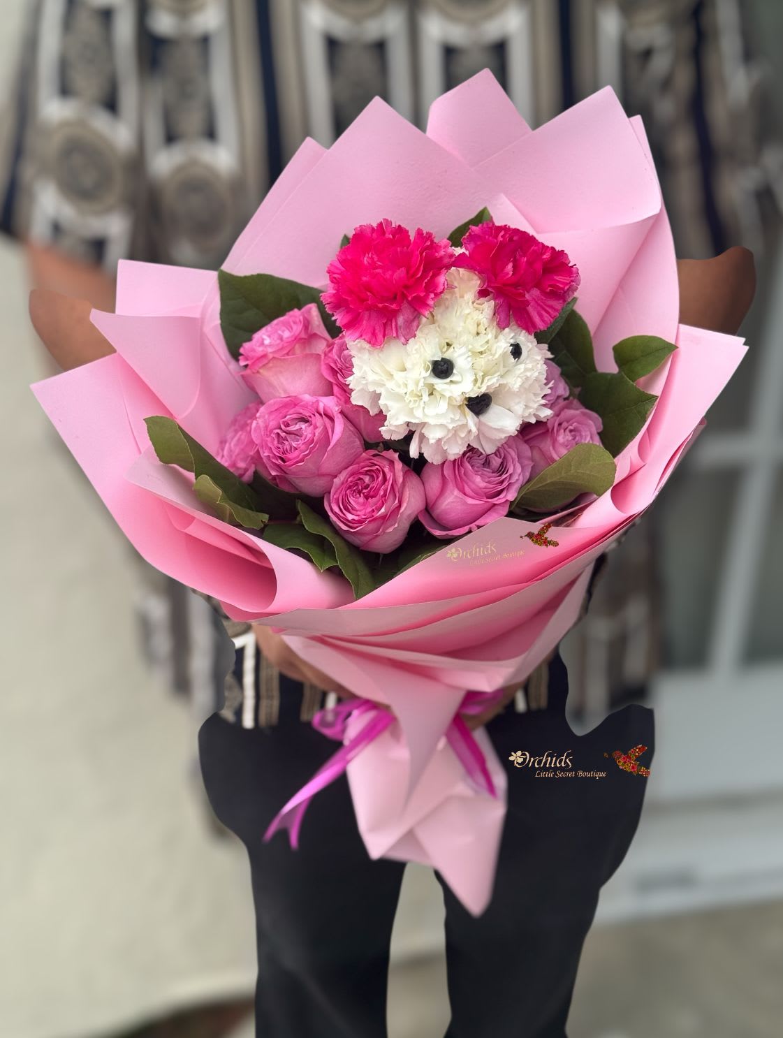 Pink bouquet with roses, carnations, and white flowers wrapped in pink paper