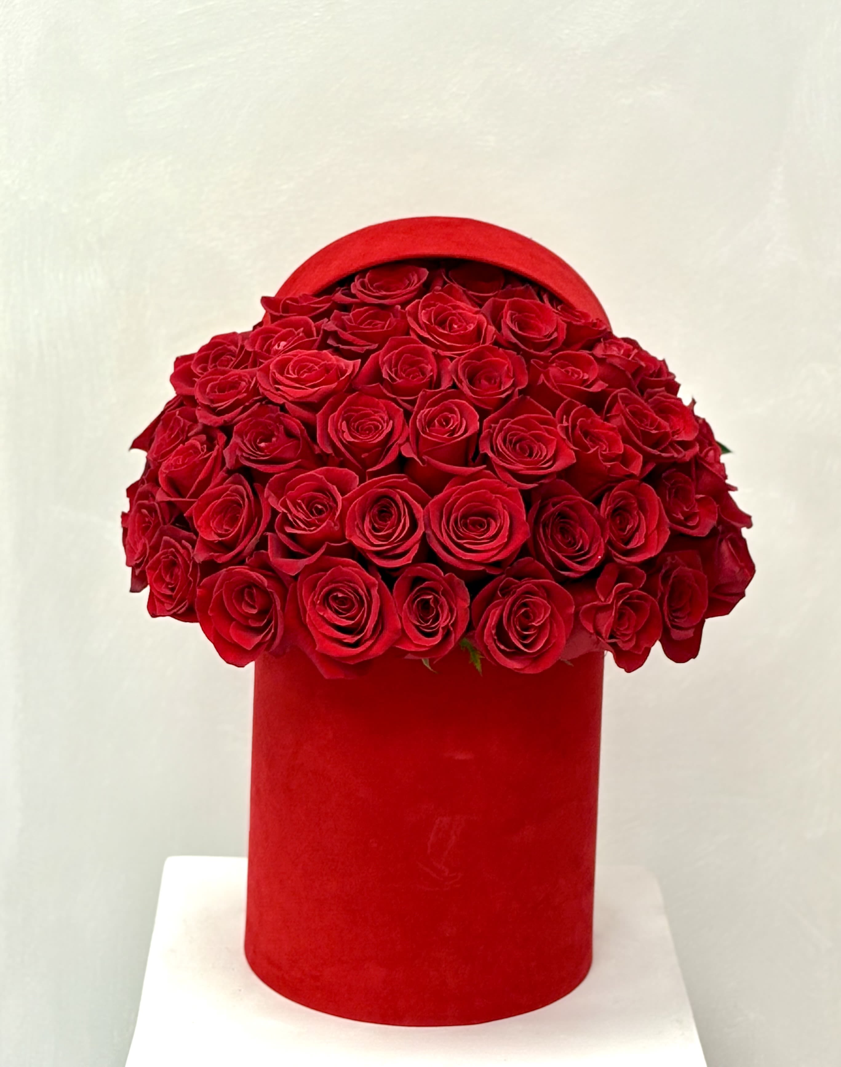 Red roses arranged in a round red hat box