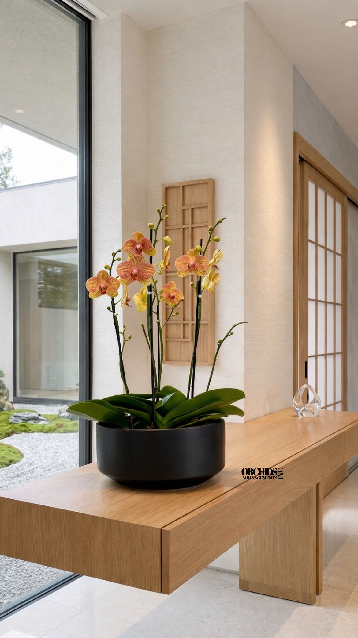Potted orchids in a black bowl on a wooden table