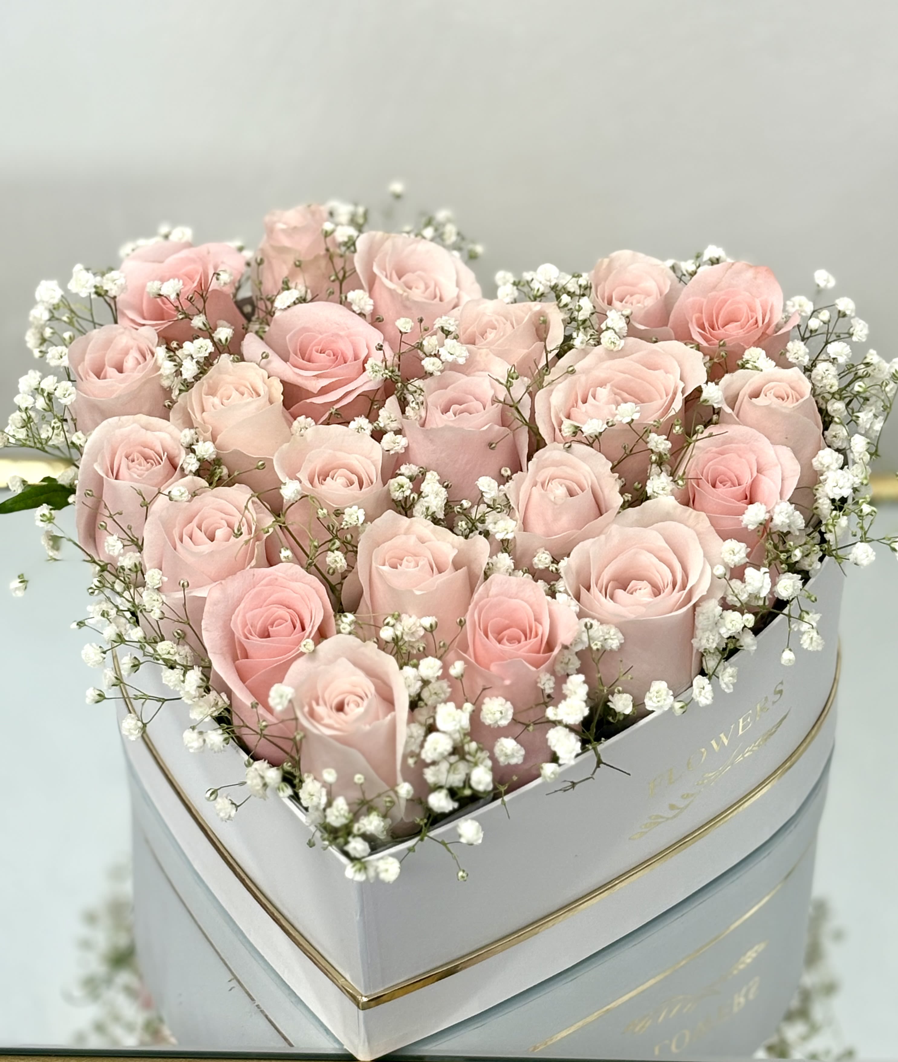 Heart-shaped box of pale pink roses with white baby's breath