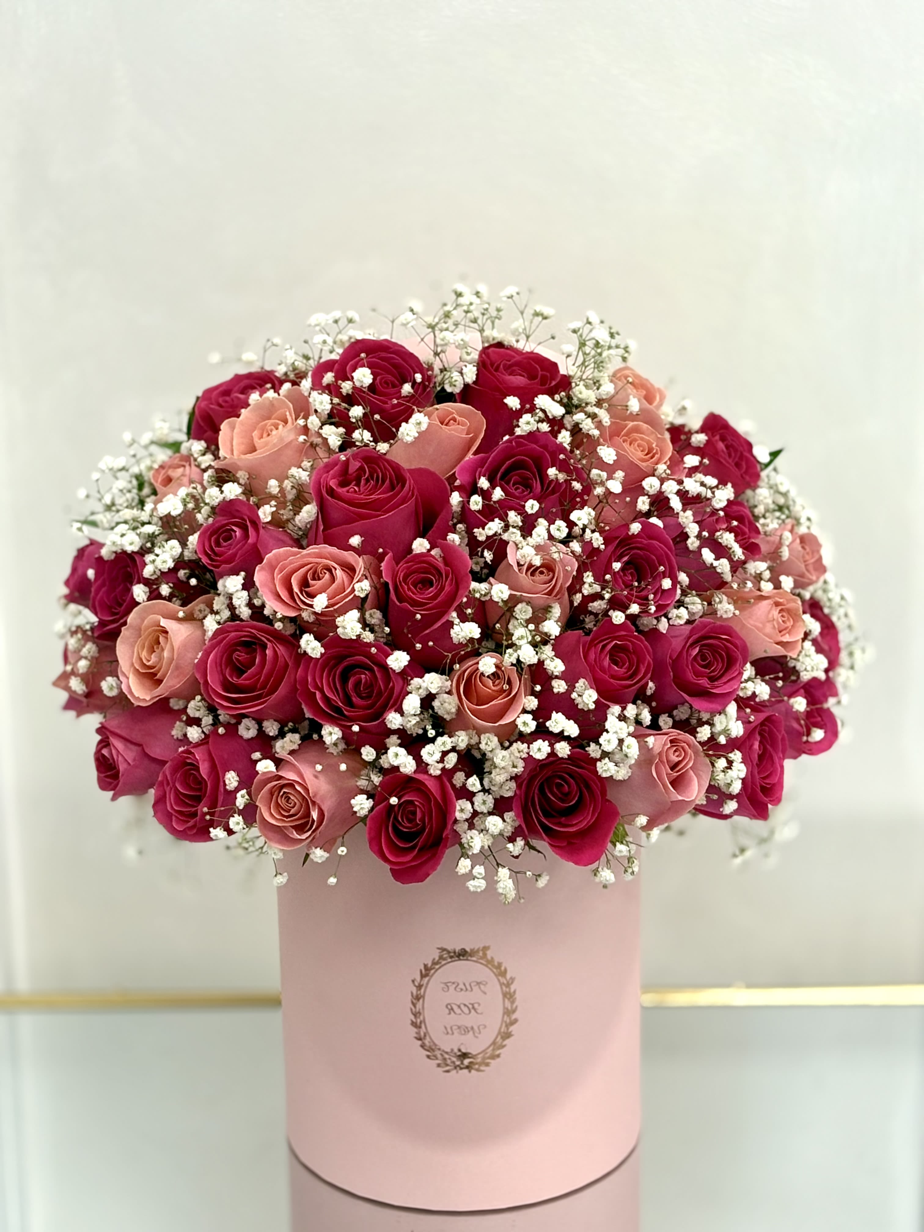 Bouquet of pink and red roses with baby's breath in a pink box