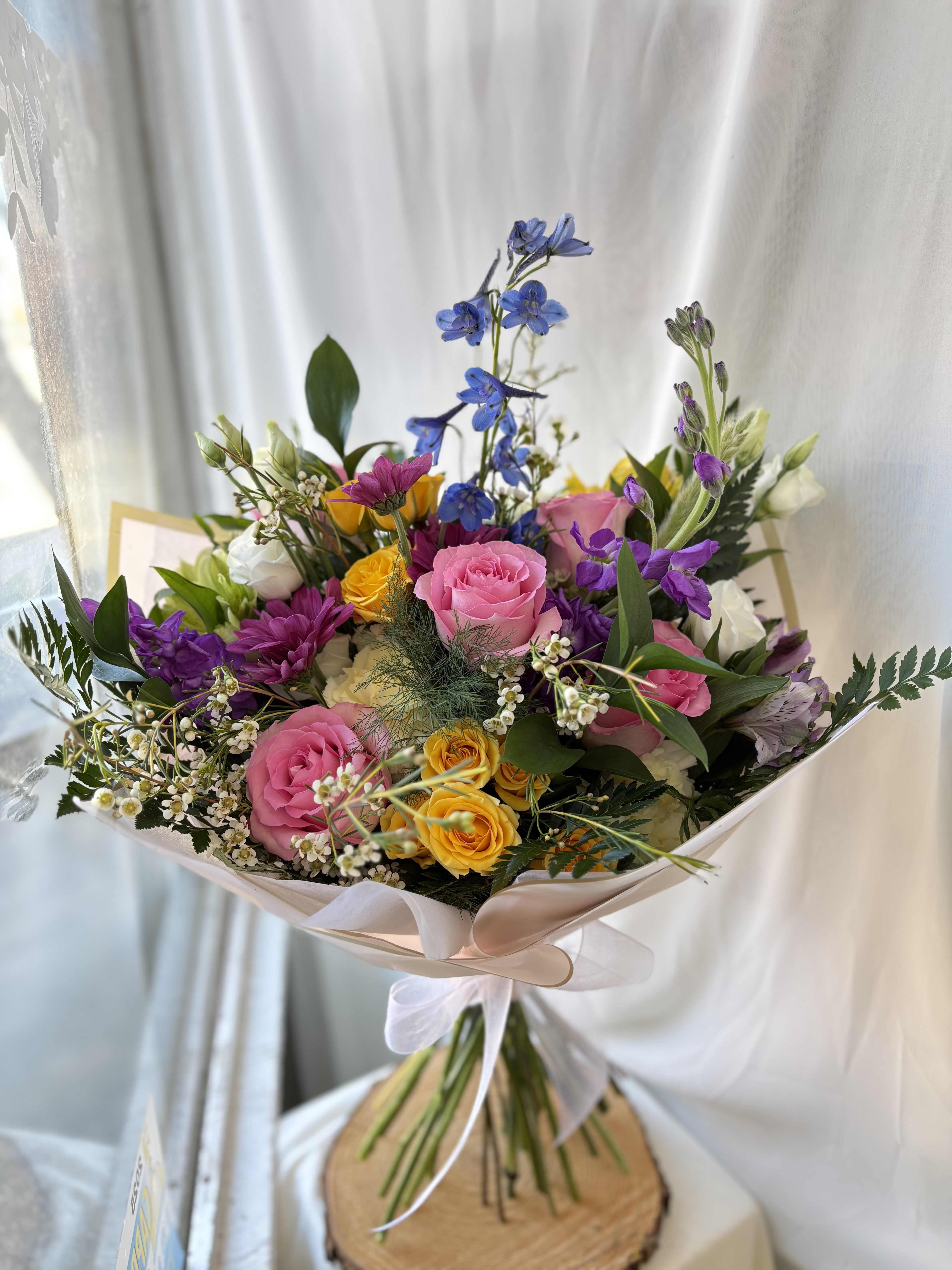 Designers Choice Wapped Bouquet - A colorful selection of our freshest seasonal blooms, wrapped presentation style! We cannot guarantee the same colors and varieties of flowers pictured, but it will give the same style and feel! Let us know if there are any specific colors or varieties of flowers you have in mind, we will try our best to accommodate!