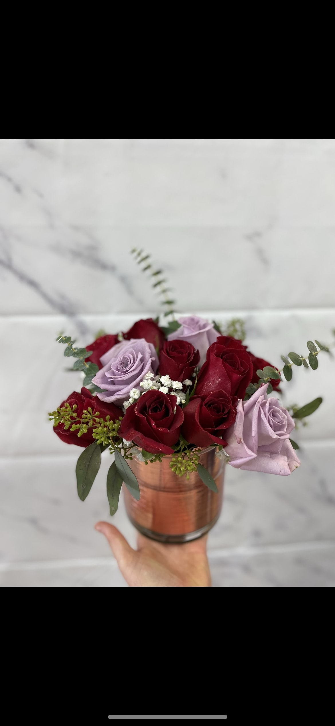 Red and lavender roses arranged in a copper vase