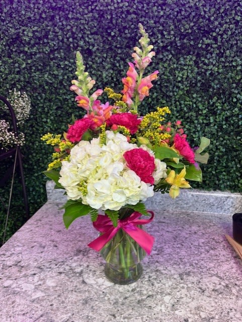 Bouquet of white and pink flowers in a glass vase with a pink ribbon