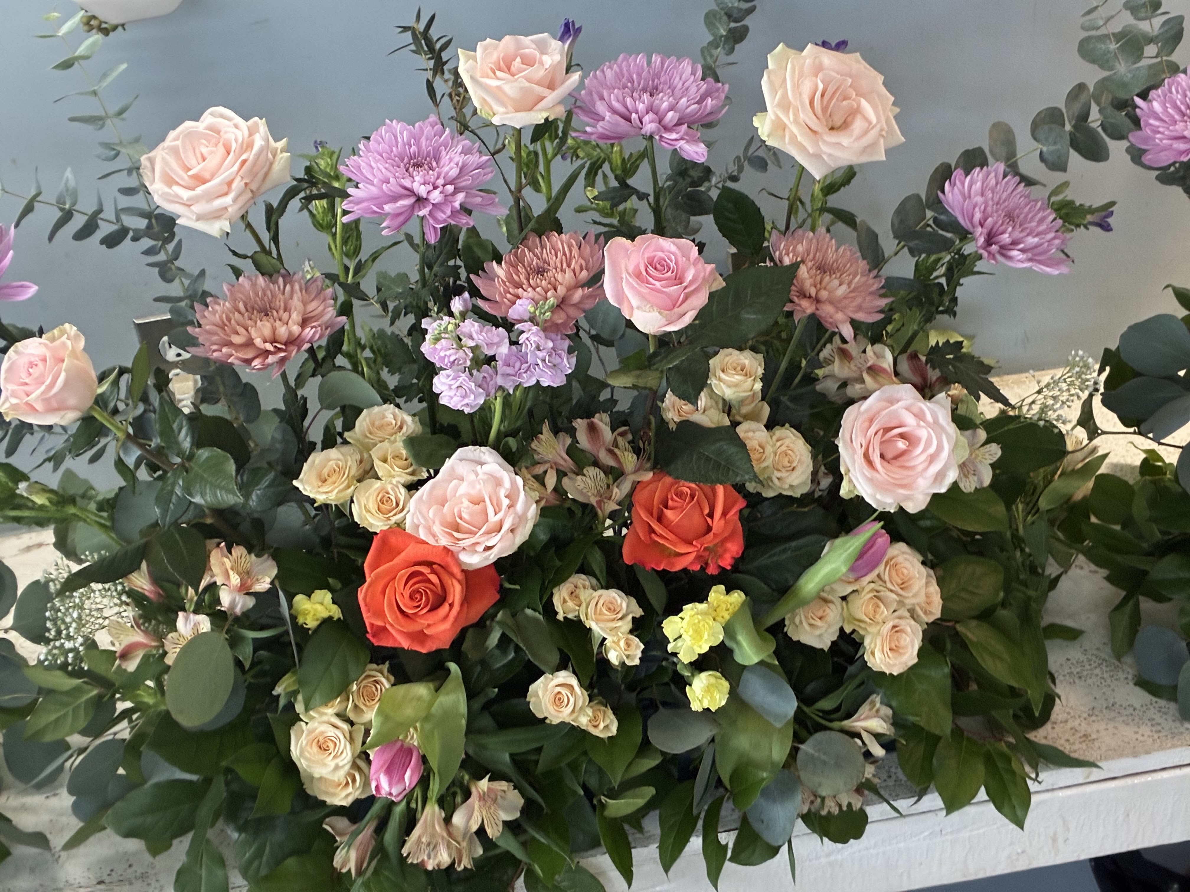 WOW - A unique urn style white vase with gold specks FILLED with White hydrangea Cymbidium orchid’s garden roses fringe roses and stock with a few Gerber Daisy’s 