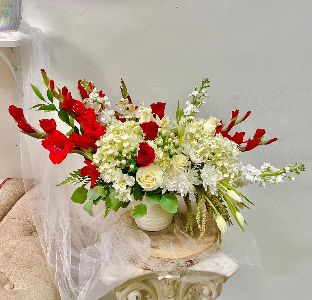 Large red and white floral arrangement in a white vase