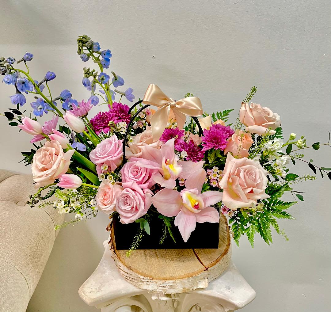 Mixed pink and blue flower arrangement in a black handled box with a satin bow