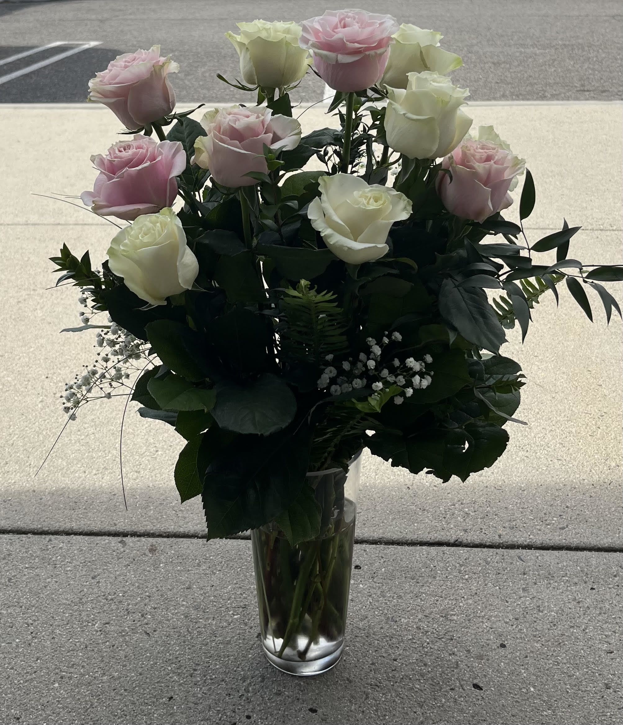 Pink and white roses arranged in a clear glass vase