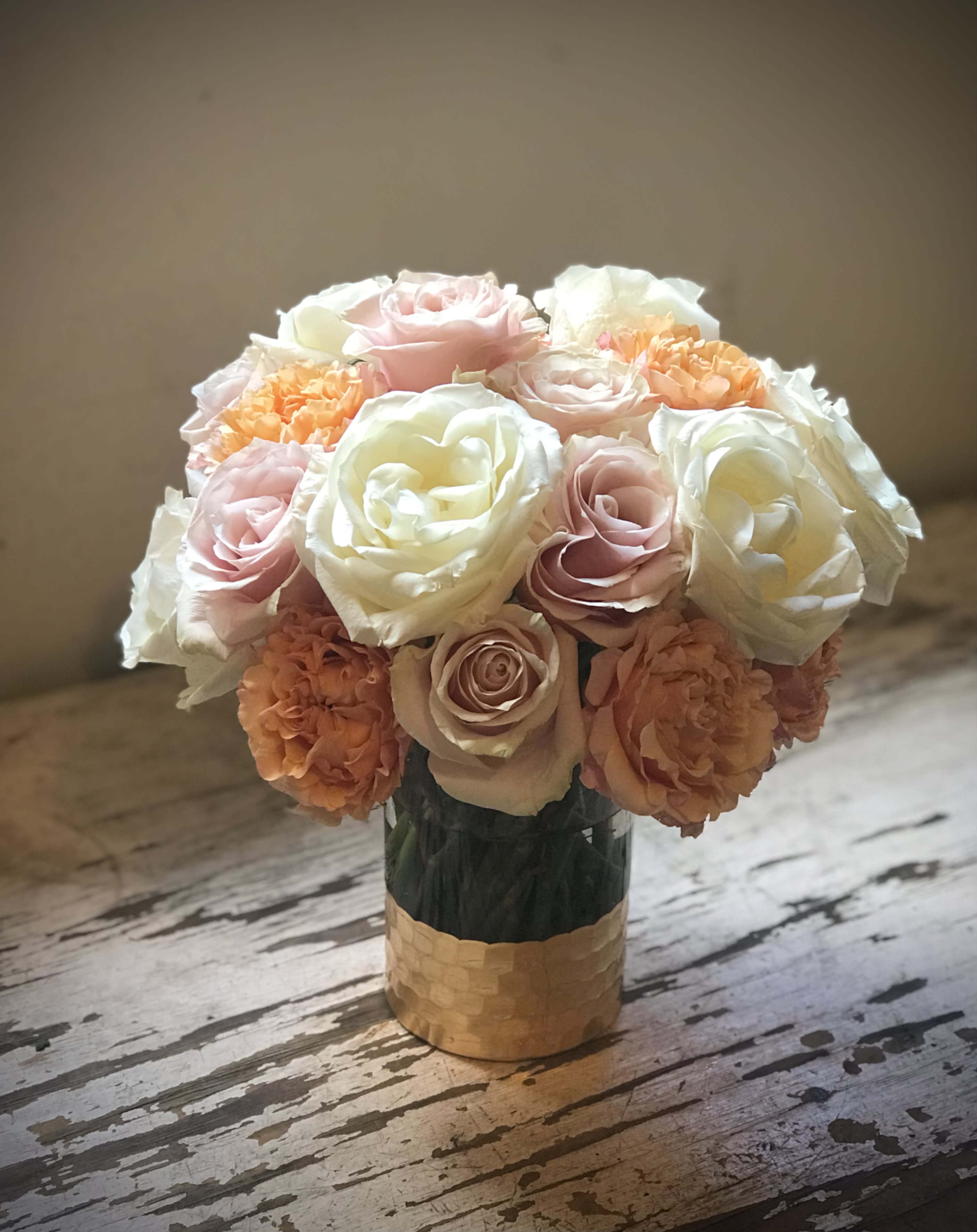 Bouquet of pale pink, white, and peach roses in a gold vase