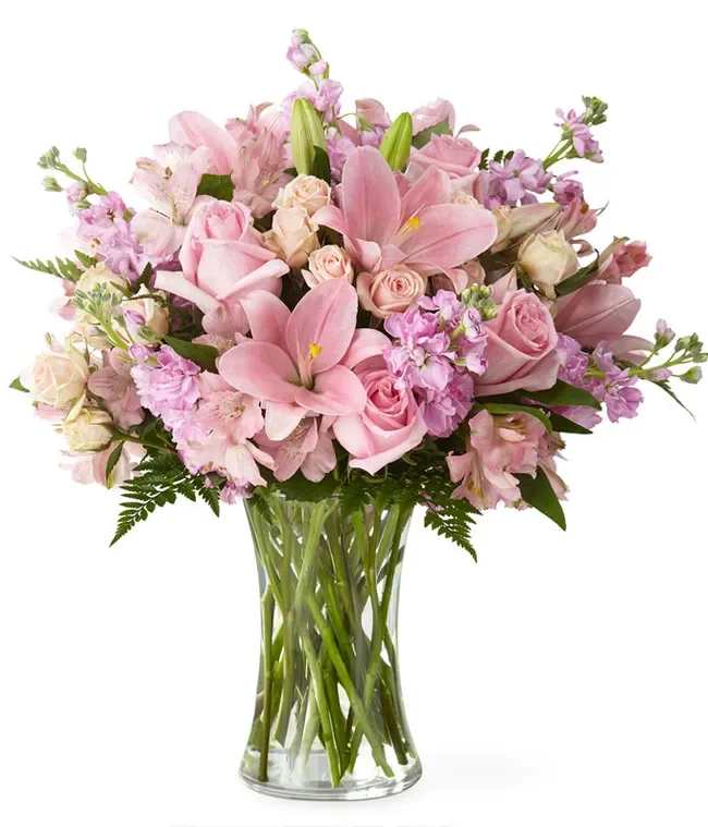 Pink roses and lilies arranged in a clear glass vase