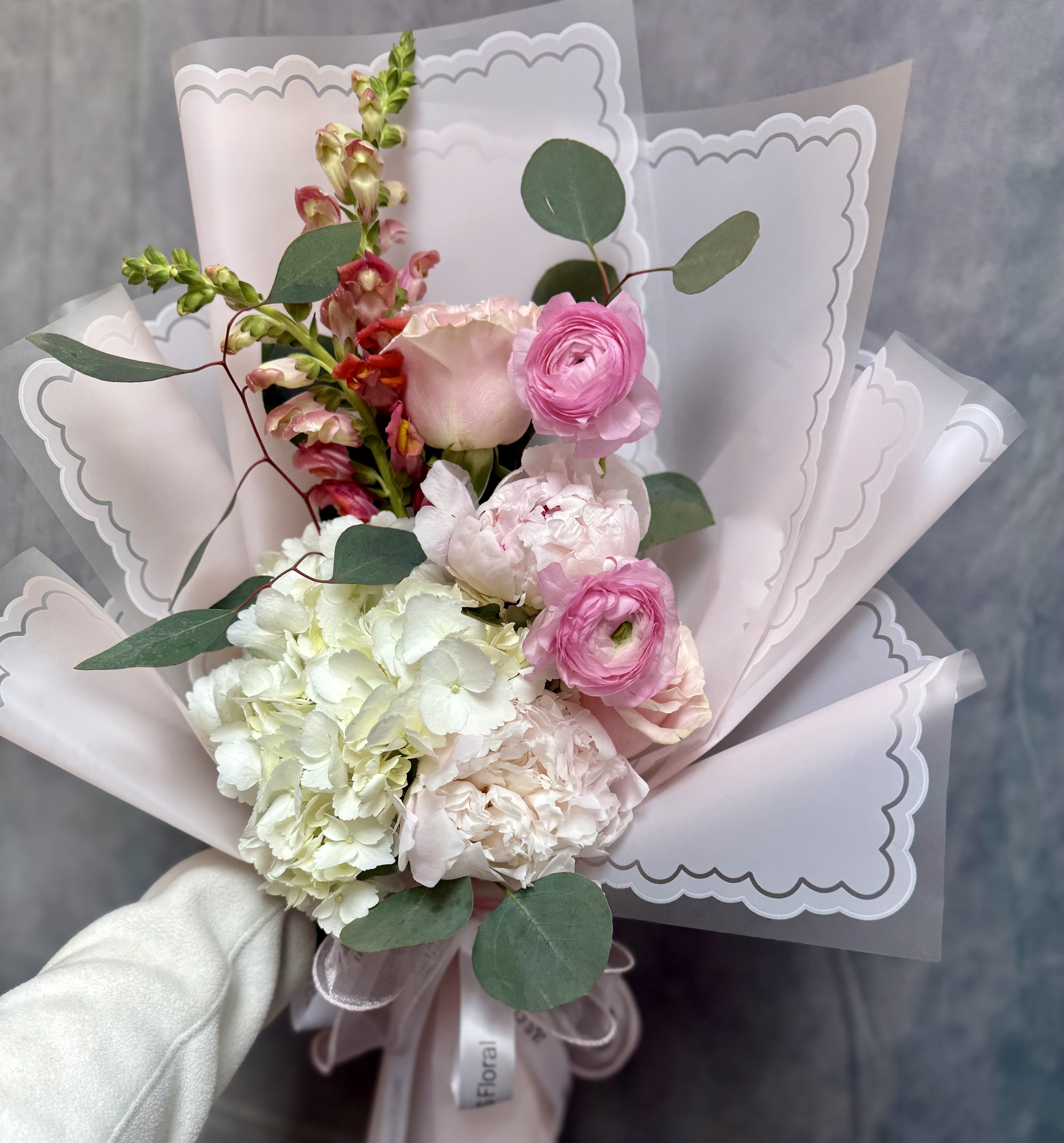 Delicate love bouquet  - A romantic hand- tied bouquet of elegant soft blooms, hydrangeas, snapdragon and touches of greenery. Wrapped in an elegant finish, perfect for expressing gentle love and heartfelt moments 