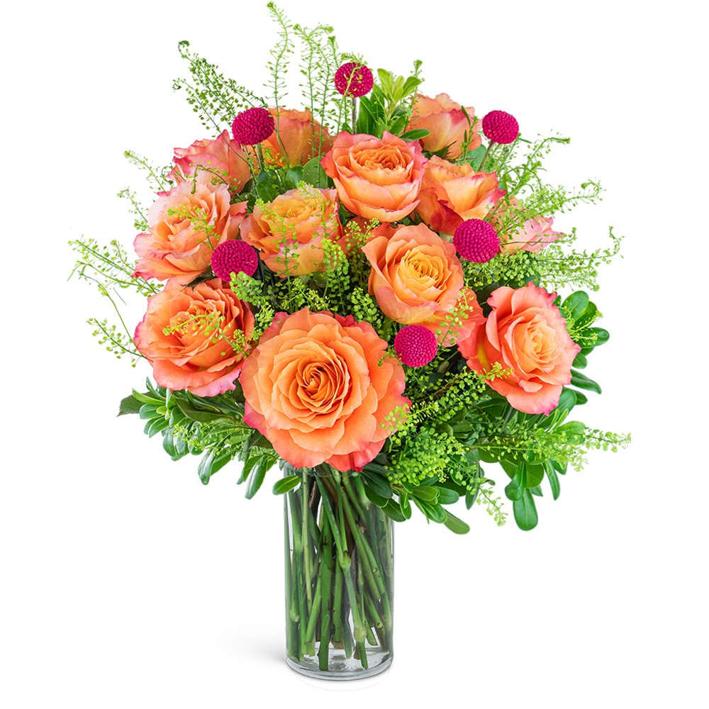 Orange roses in a clear glass vase with pink accent blooms