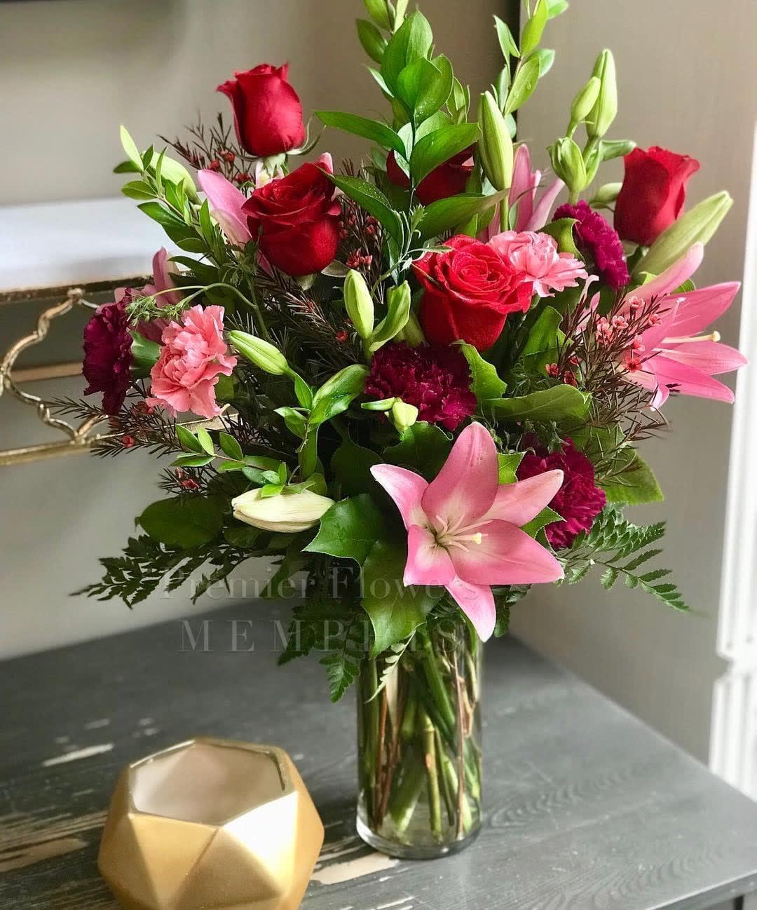 Bouquet of red roses, pink lilies, and carnations in a glass vase