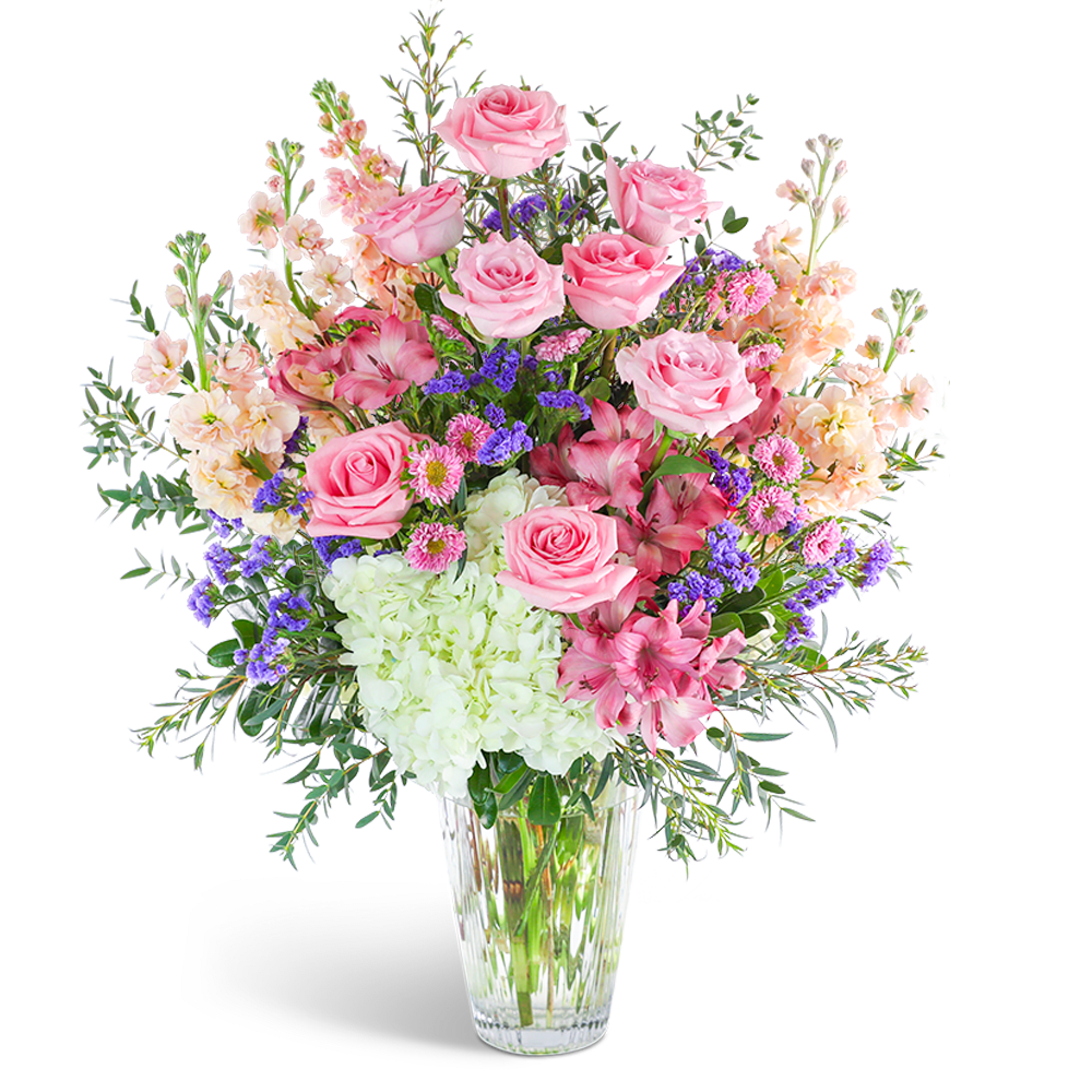 Pink roses and mixed blooms arranged in a clear glass vase