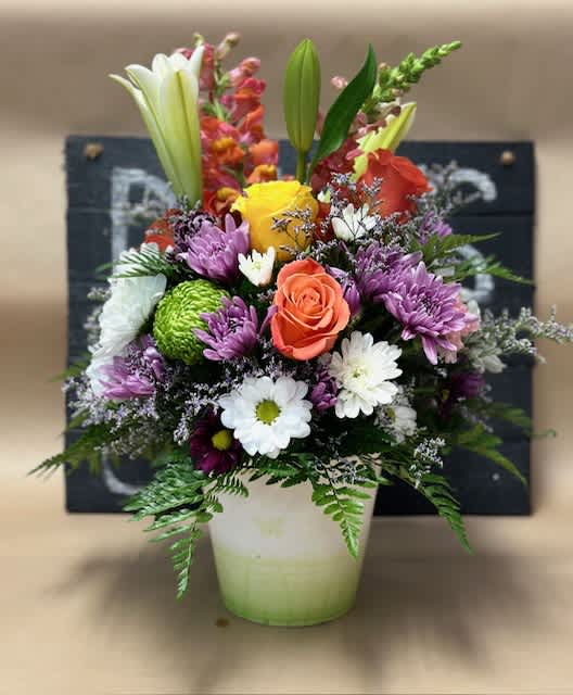 Mixed bouquet in a white vase with lilies, roses, and daisies