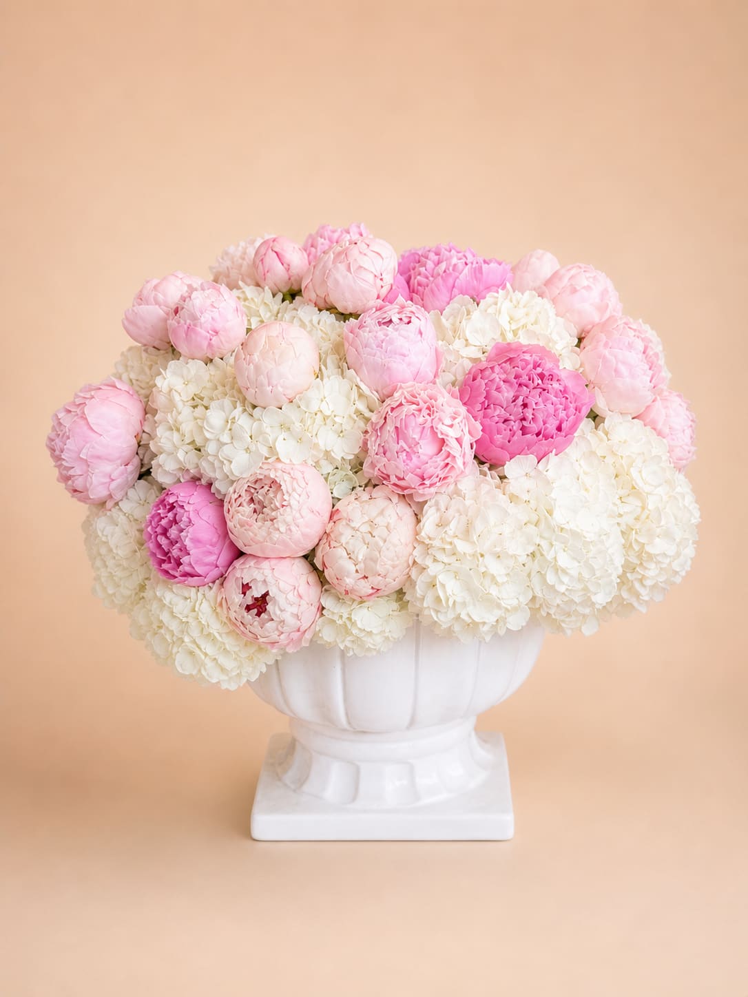 Peony Cloud - A soft, dreamy composition that feels as light as air, Peony Cloud brings together lush blush and ivory peonies nestled into a bed of cloud-like hydrangea. Accented with delicate greenery, this arrangement creates a full, rounded silhouette that feels both romantic and effortlessly refined. Designed in a classic white vessel, it’s a timeless statement piece—perfect for celebrating life’s sweetest moments or adding a touch of elegance to any space.
