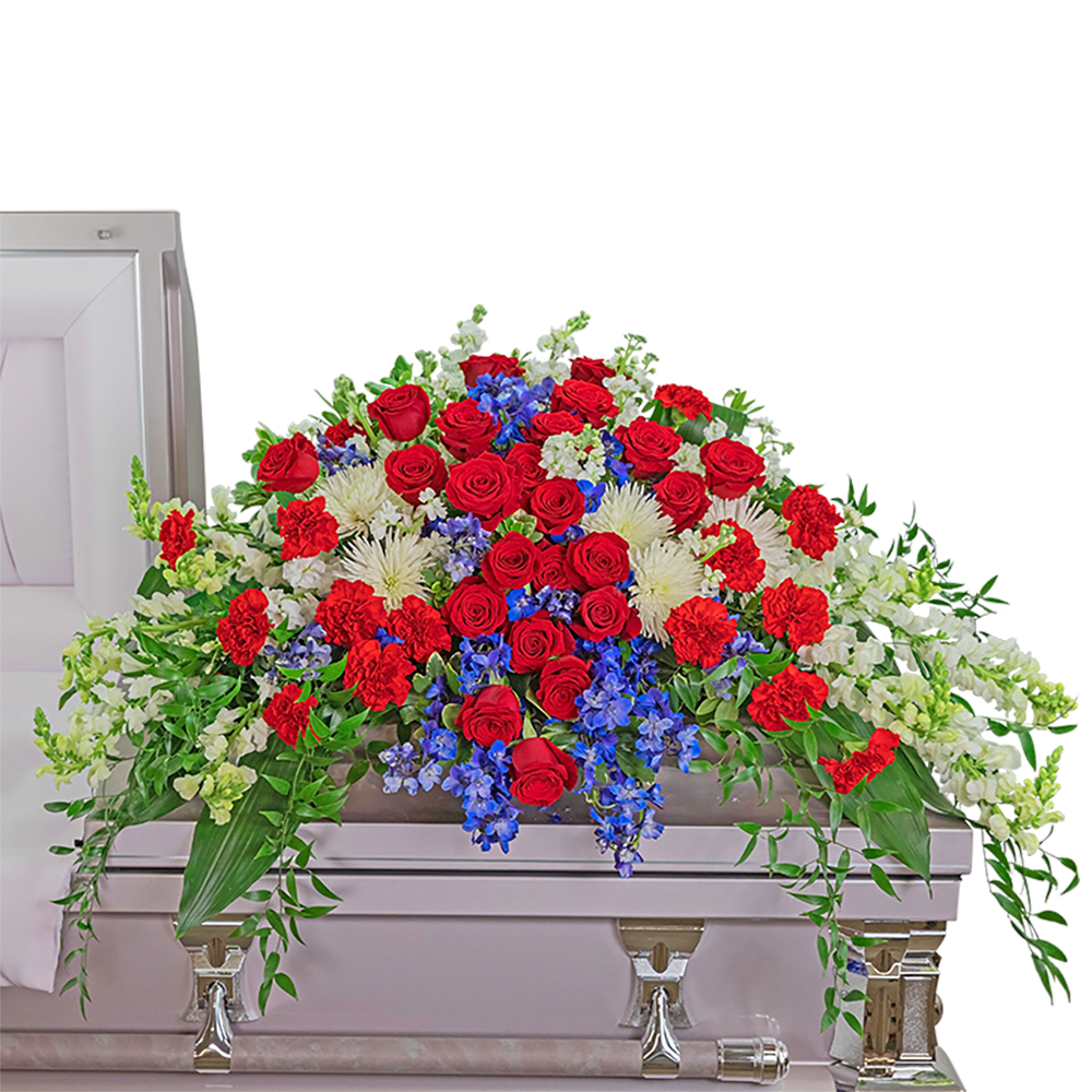Valiant Honor Casket Spray - This beautiful red, white, and blue casket spray honors the valiant effort of the ones who served our country  It is filled with red roses and carnations, blue delphinium, and white snapdragons surrounded by a variety of premium foliage. The Casket Spray is typically provided by the spouse or the immediate family as a heartfelt memorial and is designed to drape over the lid of the casket for a funeral or memorial.  The image shows the Deluxe arrangement.