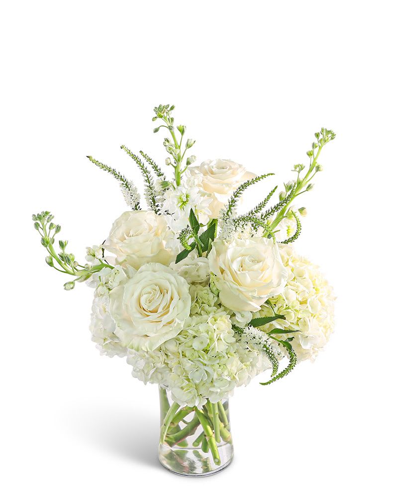 White roses and hydrangeas in a clear glass vase