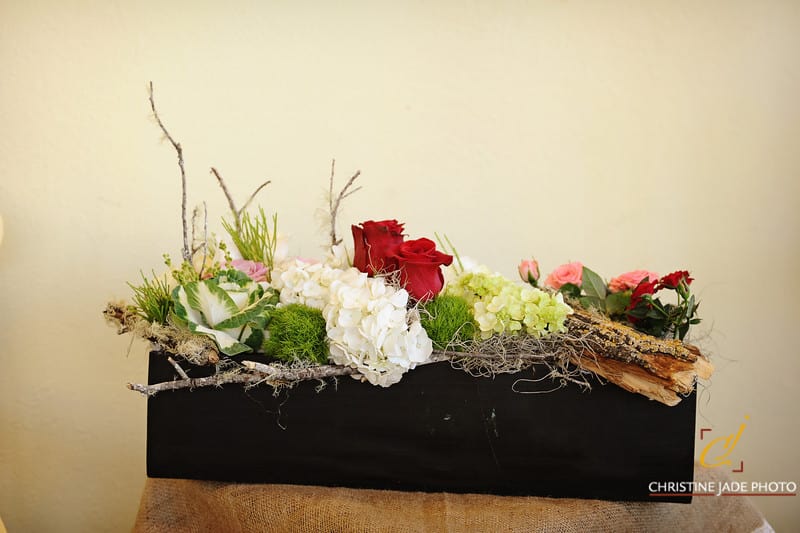 Low floral arrangement with red roses, white hydrangeas, and pink blooms in a black container