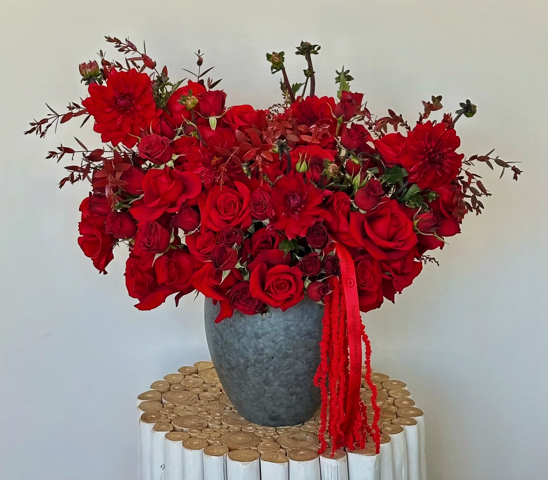 Red rose and dahlia arrangement in a gray vase