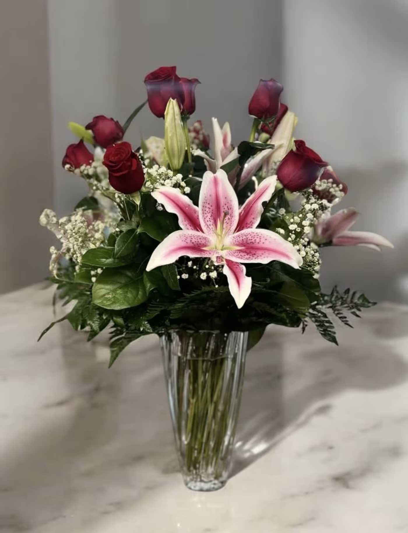 Pink lilies and red roses in a clear glass vase
