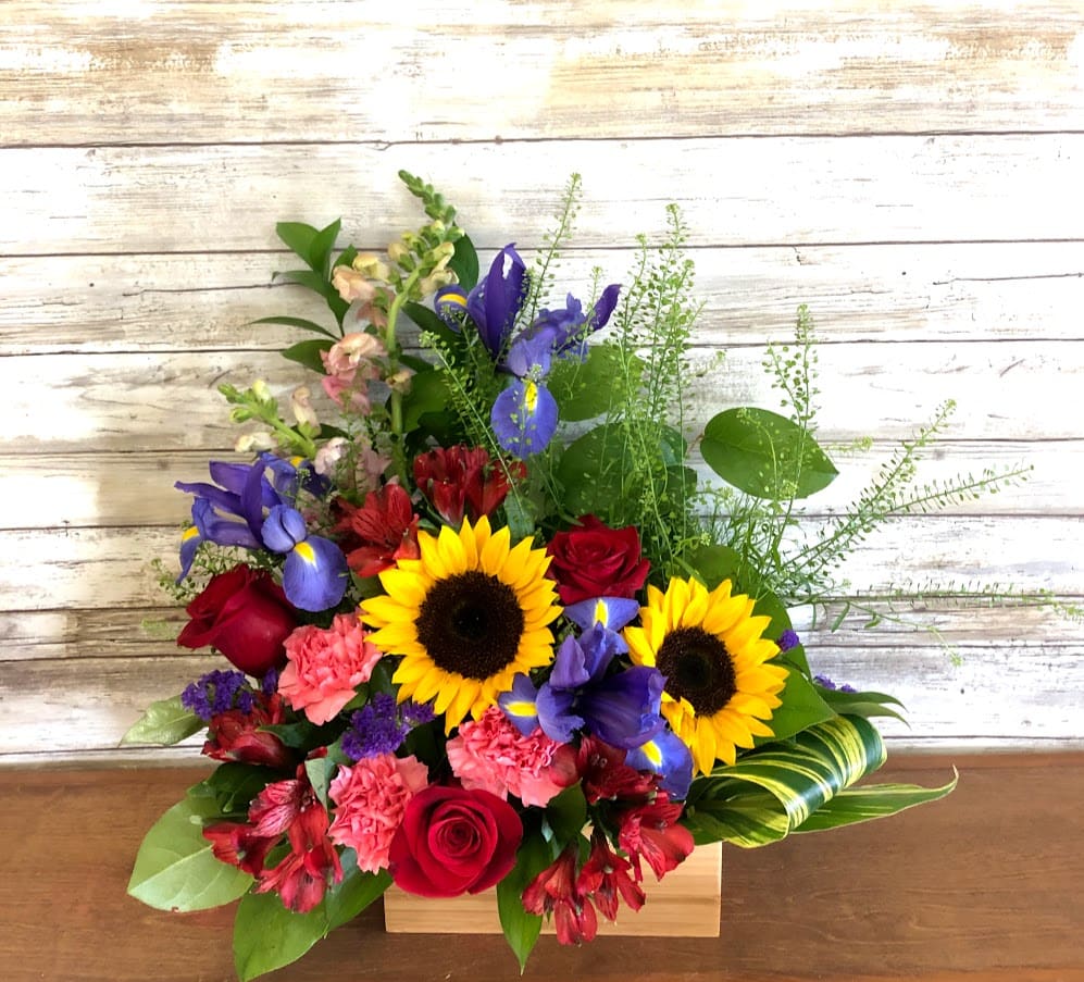 Mixed bouquet with sunflowers, red roses, purple irises, and pink carnations