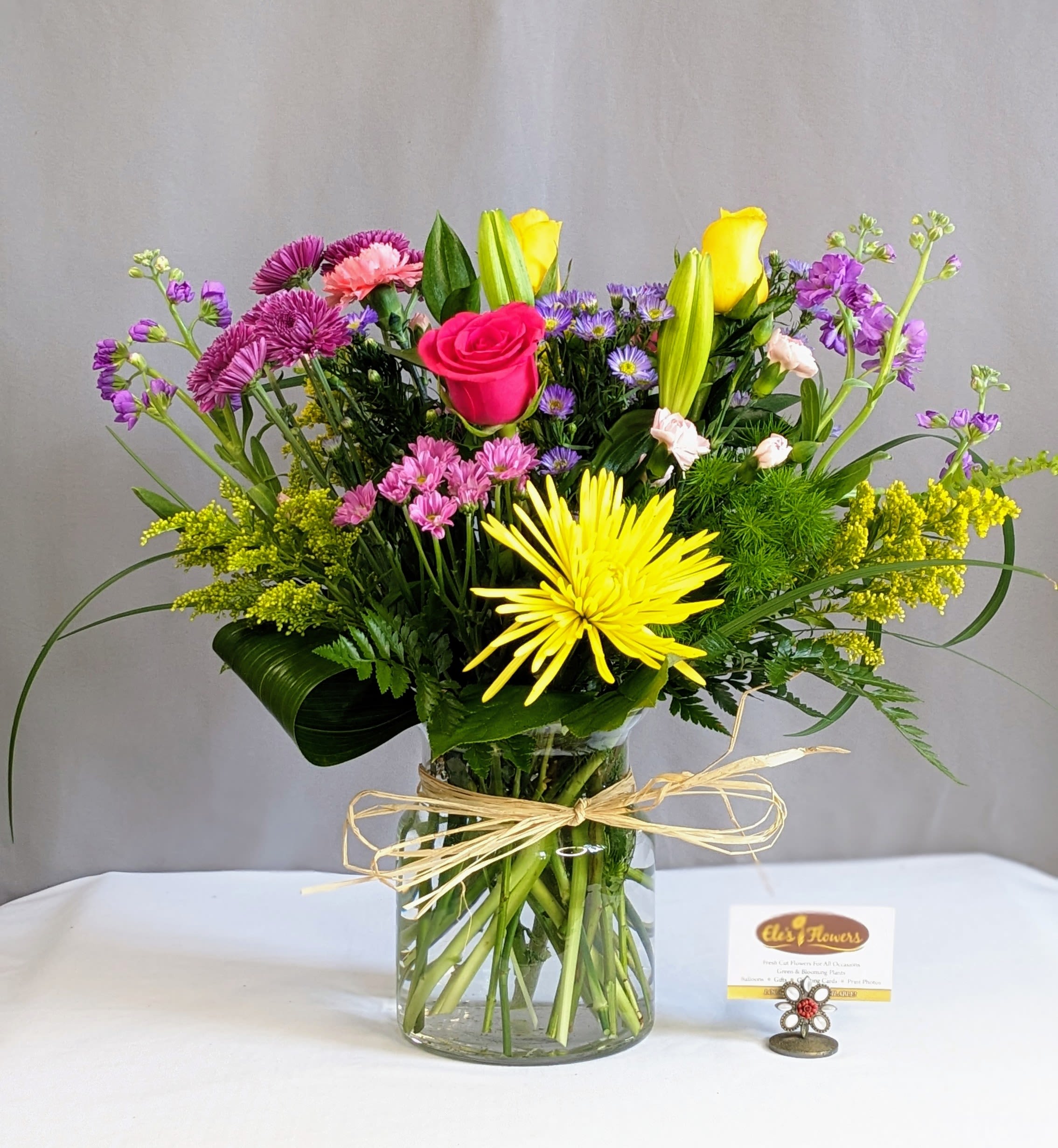 Kind Paitence - Softly radiant and full of meaning, Kind Patience is a Mother’s Day arrangement that beautifully reflects warmth, grace, and enduring love. Featuring a harmonious blend of sunny yellow lilies, delicate lavender roses, cheerful yellow spray roses, and textured purple and lavender cushion poms, this design is thoughtfully accented with fragrant purple stock and lush, fresh greenery.  The gentle contrast of golden hues and calming purples creates a peaceful yet uplifting presence—perfect for honoring the quiet strength and kindness that mothers bring into our lives every day. Arranged in a coordinating vase or vessel, each piece is crafted to feel balanced, elegant, and heartfelt.  Please note that flower varieties and container may vary based on availability, but the overall color palette, style, and sentiment of Kind Patience will always be preserved.  Approximate Dimensions: 19"H x 22"W