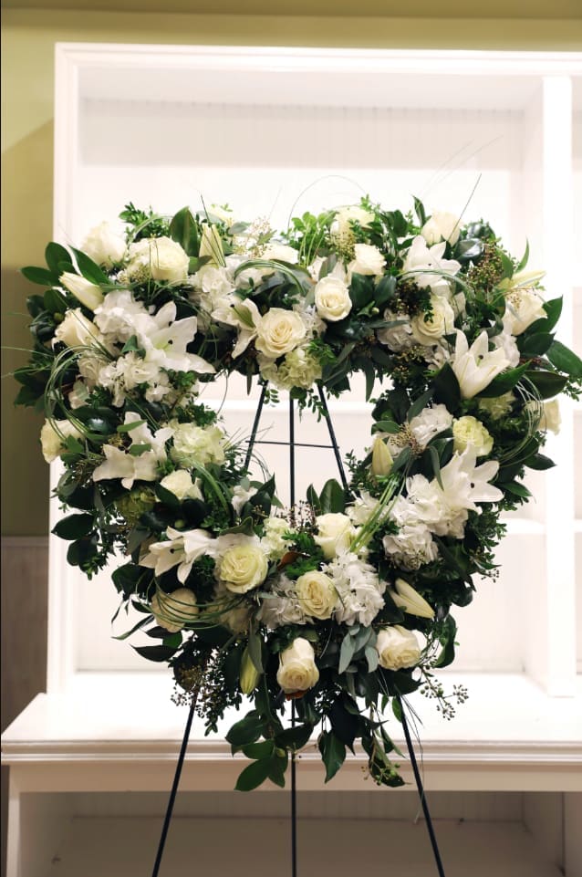 Heart-shaped white floral wreath on a stand