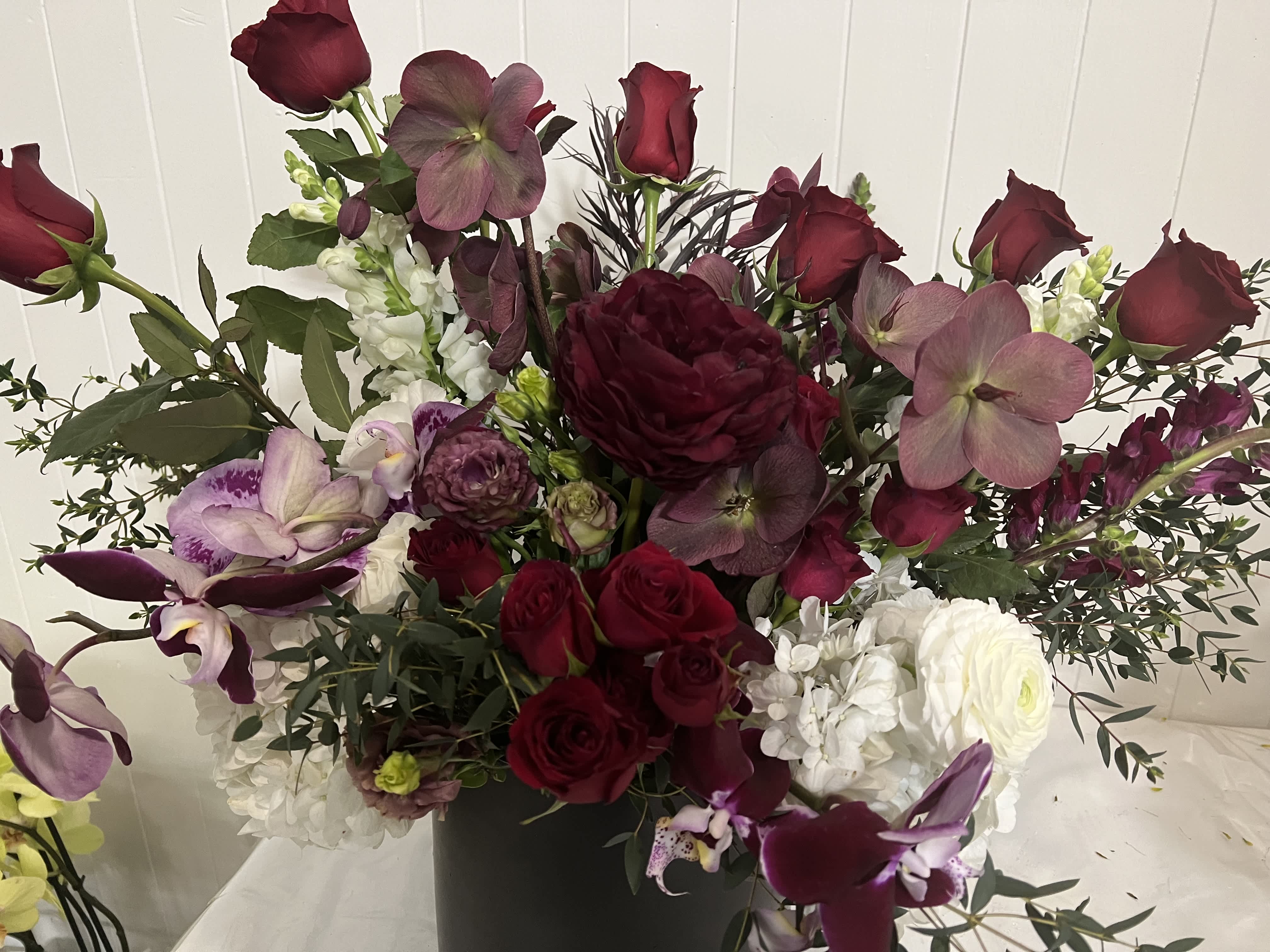 Deep burgundy and white floral arrangement in a black vase