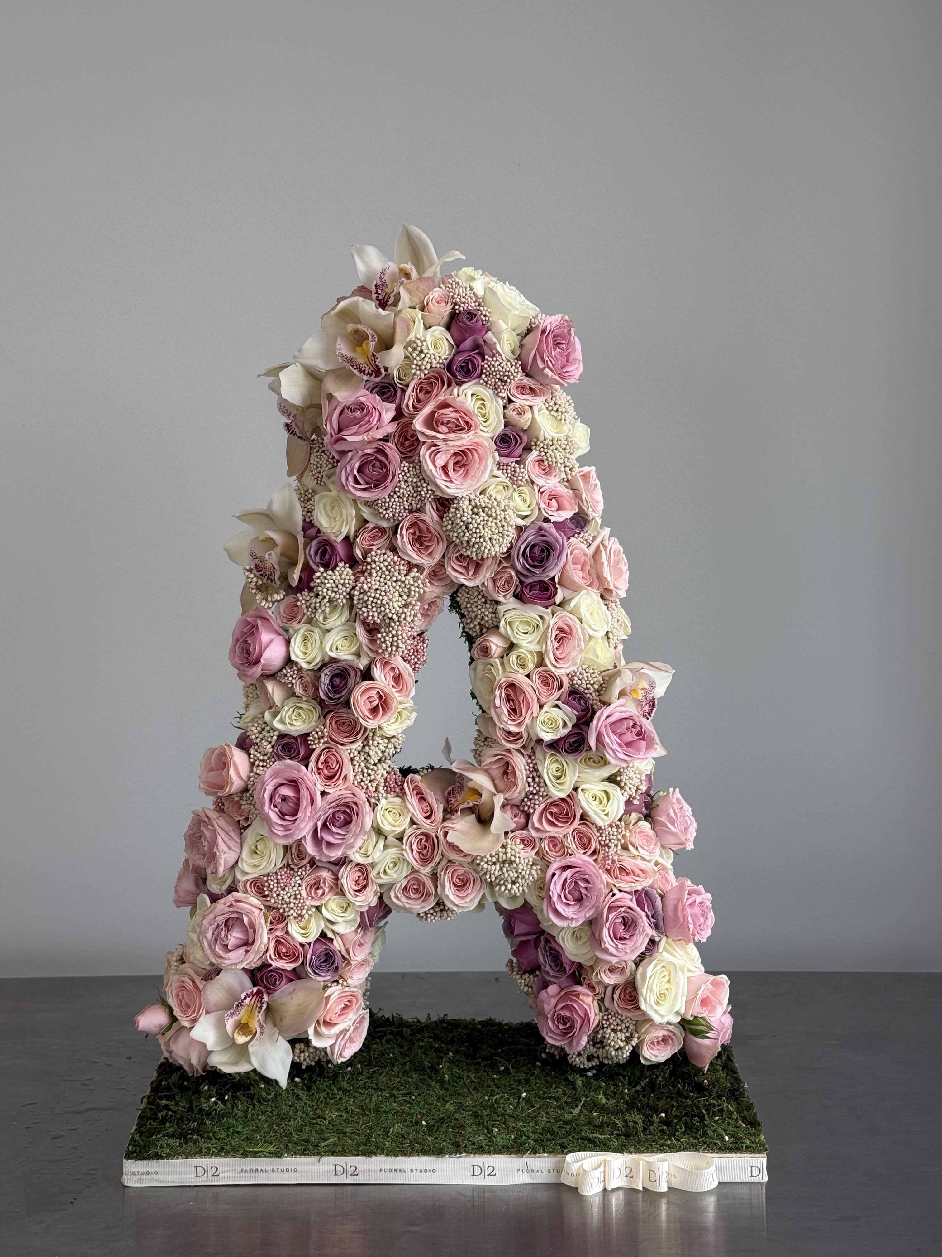 Large floral letter A covered in pink and white roses and orchids