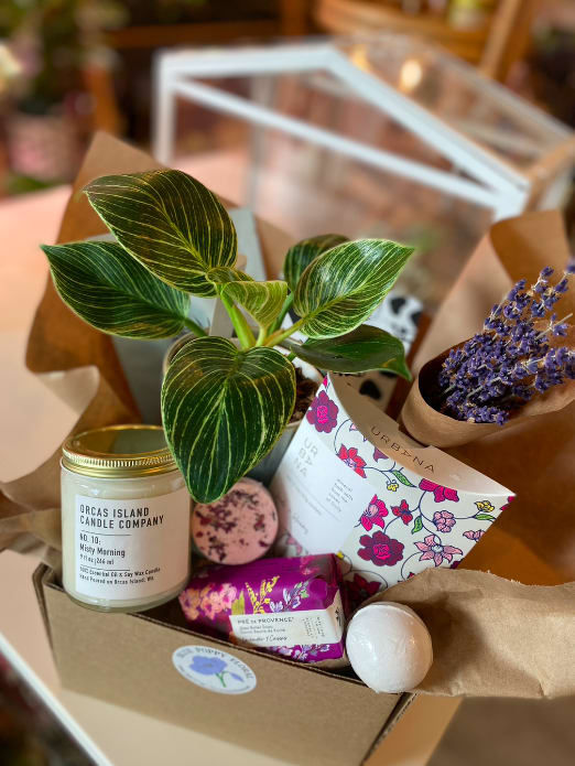 Gift box with a potted plant, candle, soap, and dried purple flowers