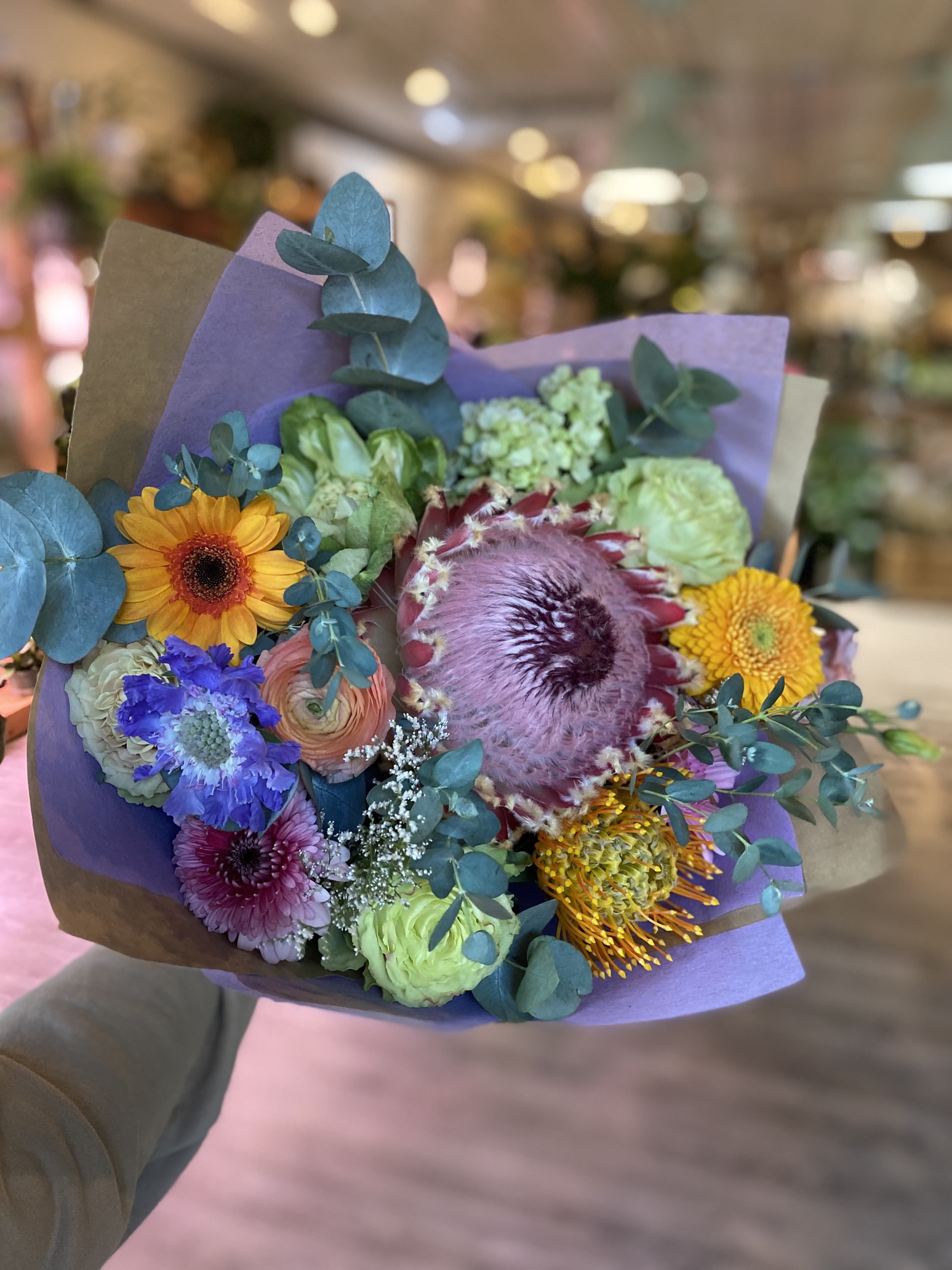 Mixed bouquet with colorful flowers wrapped in purple paper