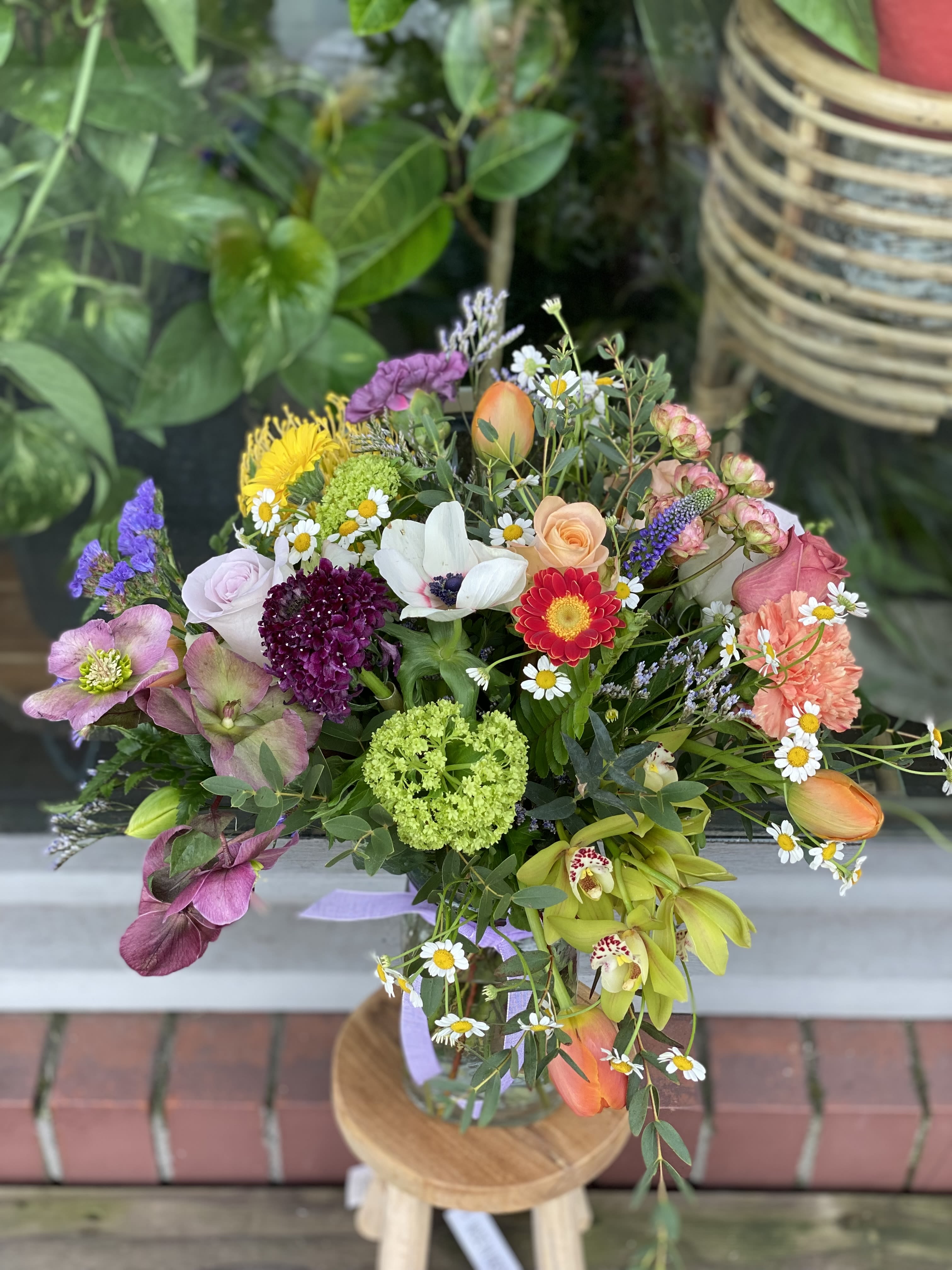 Mixed bouquet with roses, daisies, and orchids in a glass vase