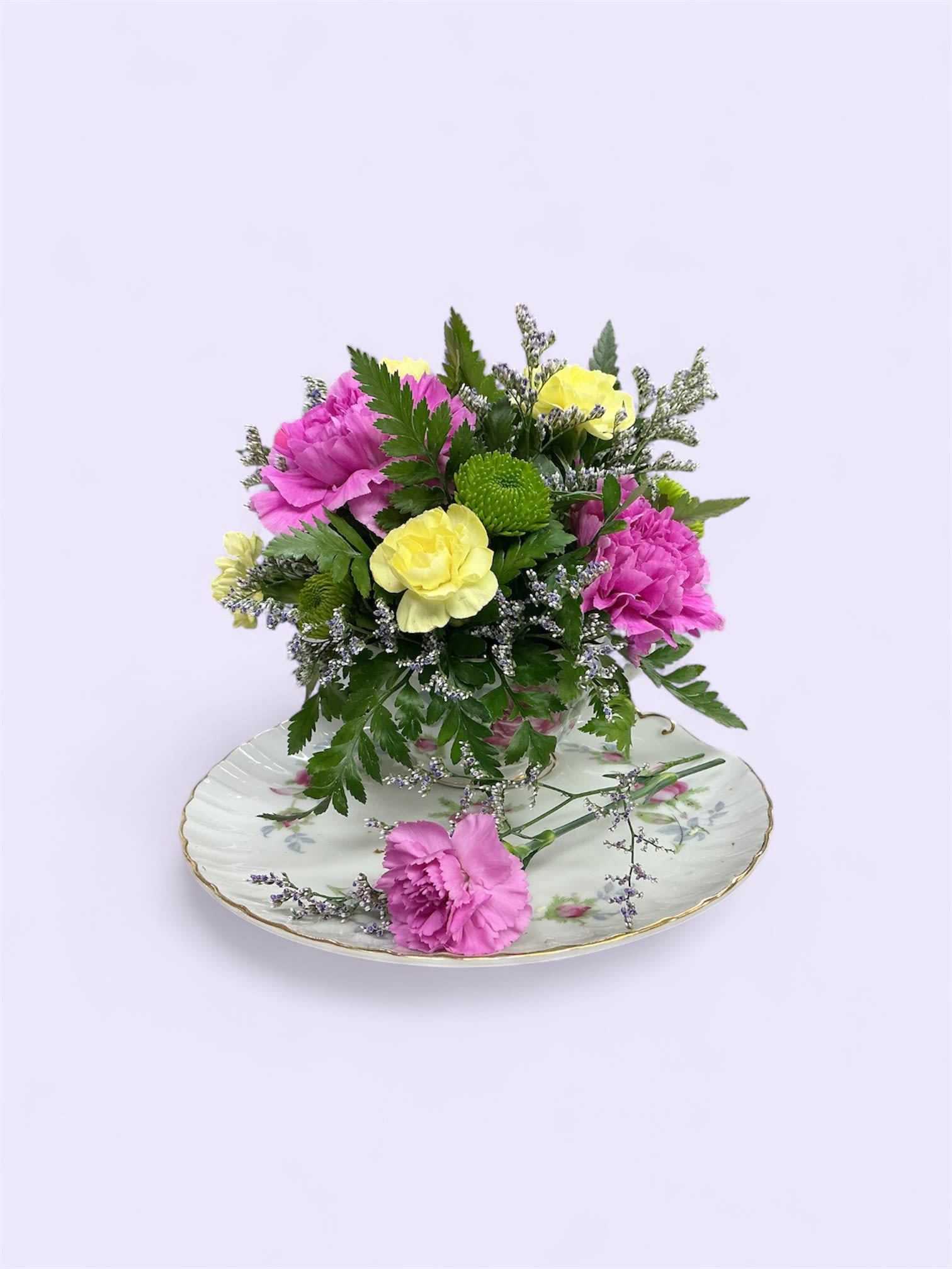Tea Time  - A sweet little vintage Tea Cup and saucer with a beautiful arrangement of pink Carnations, yellow Mini Carnations, green Buttons, and Limonium with fresh greens. Perfect for all occasions. (LIMITED QUANTITIES AVAILABLE)