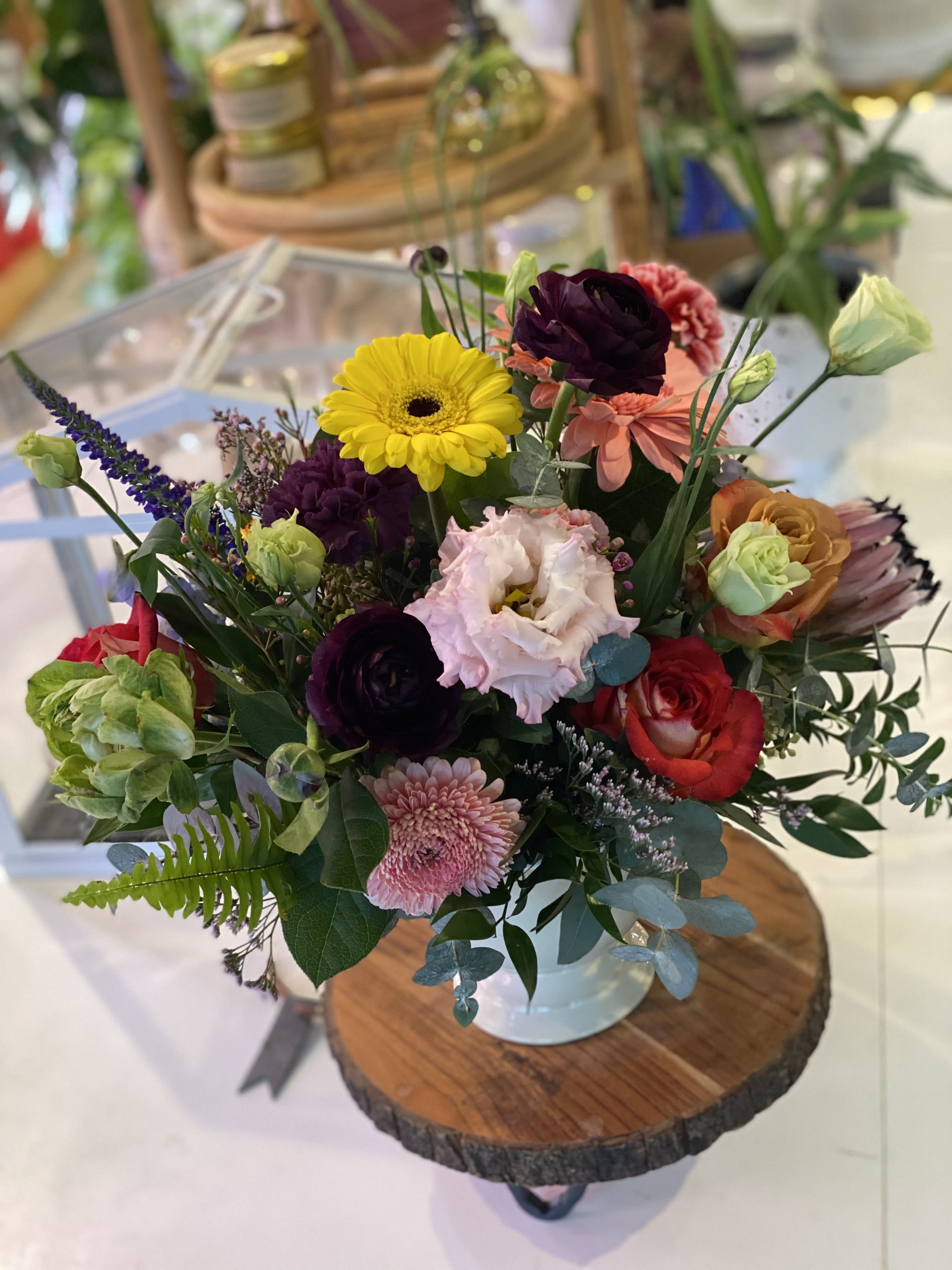 Mixed bouquet in a white vase with bright yellow, pink, red, and purple blooms