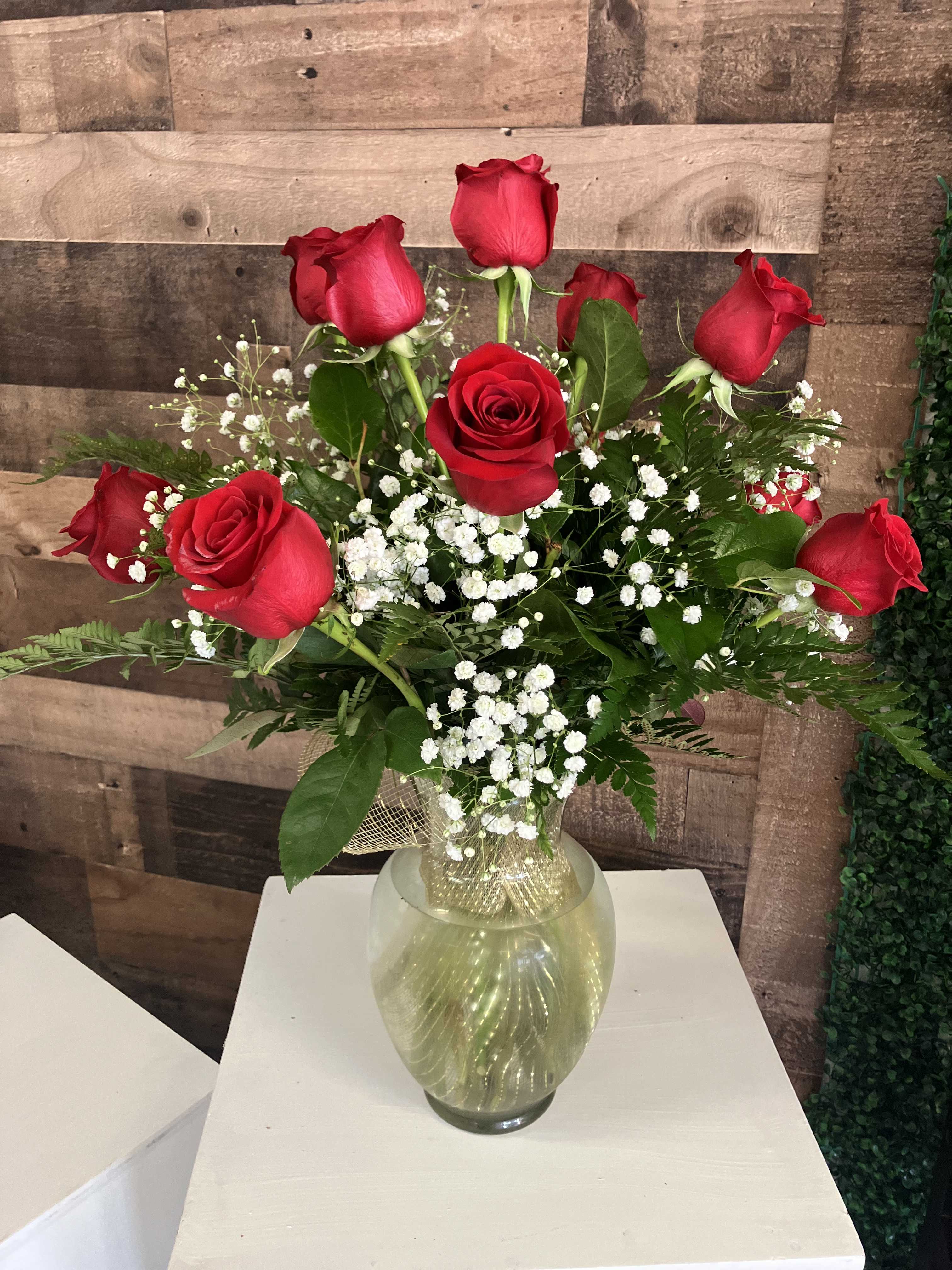 Red roses arranged in a clear glass vase with white baby's breath