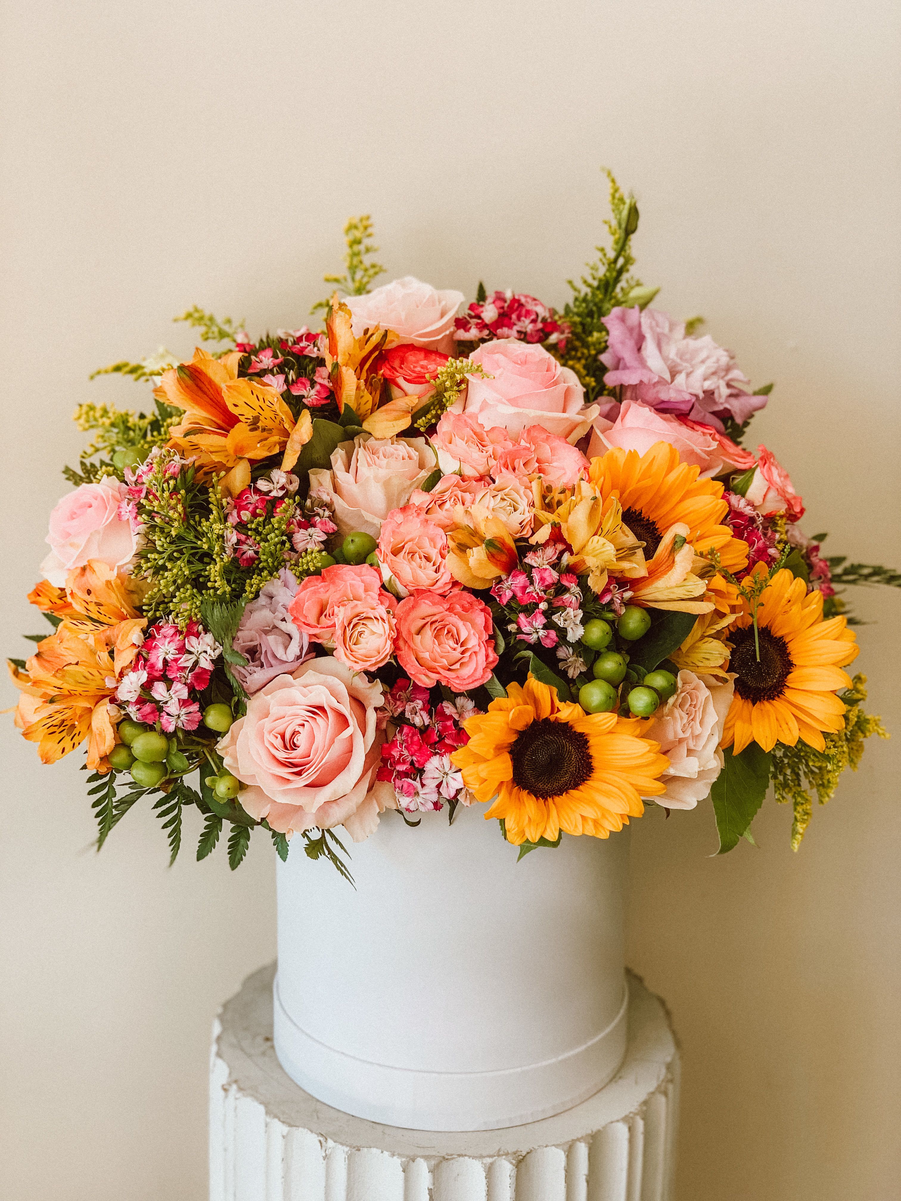 Velvet Sunset - Product Information Theme Colors: Pink, yellow, and Green.  Featured Blooms: Roses, Alstroemerias, Sun flowers, and greeneries in a box  HK Flowers have a uniqueness of florals and seasonal blooms, certain flowers or colors may not be available as each season affects the availability, color, size, and shape of each floral bloom. Some flowers may be substituted accordingly.  Photos are used as a reference for the color palette and is NOT indicated of the final product. We ask for your trust in us that we will pick out the best seasonal available blooms, while still capturing the arrangements' theme and colors mentioned above.