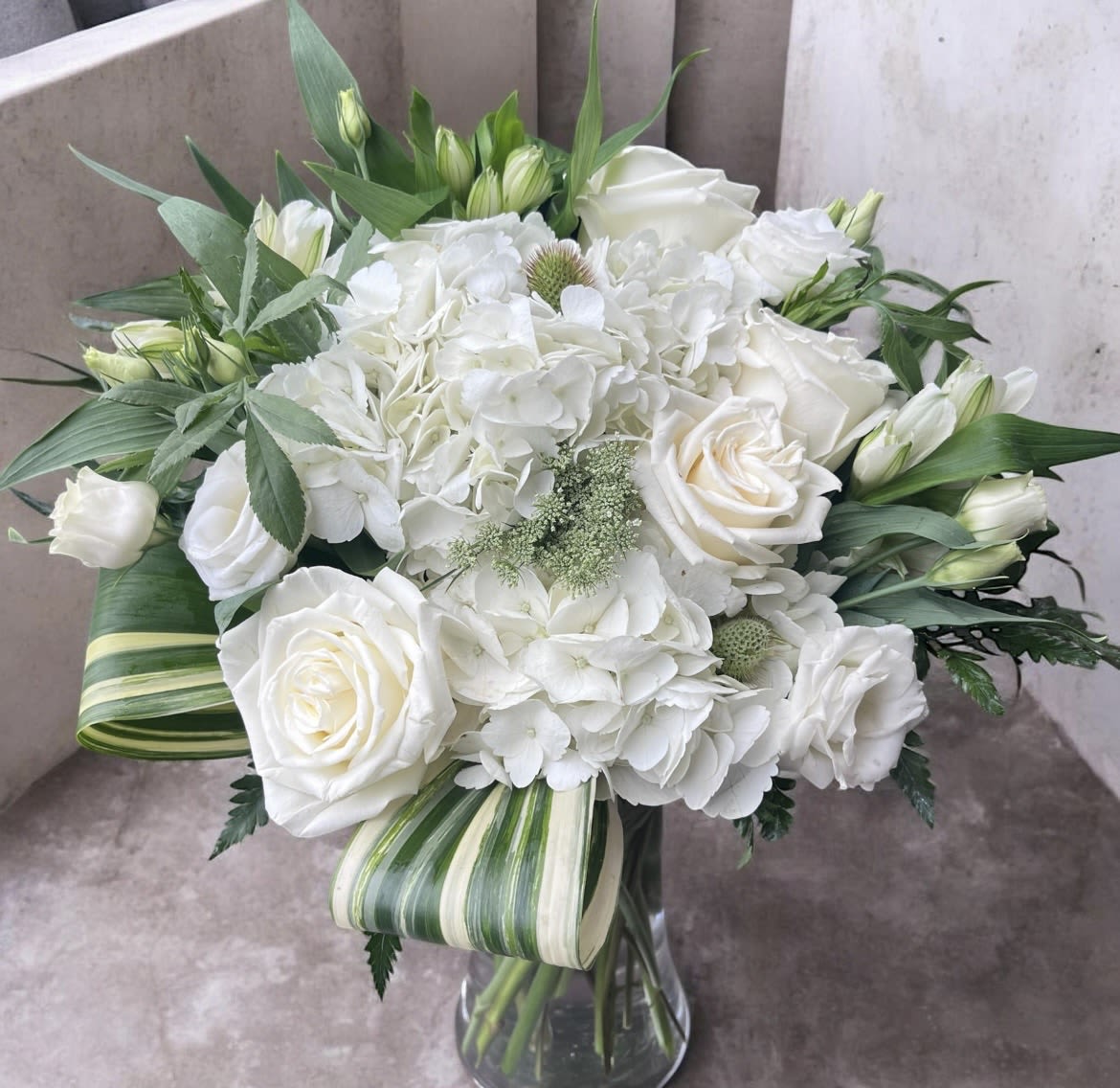 White Enchantment - This arrangement has alstroemeria, roses, hydrangea, aspidistra leaves, Lisianthus and greenery.