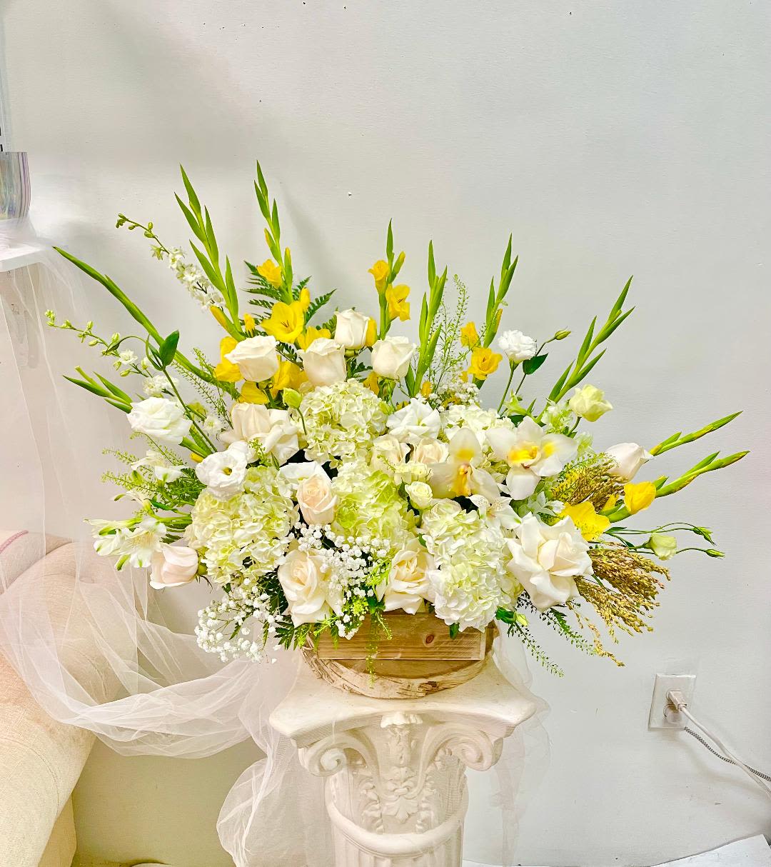 Large white and yellow floral arrangement in a wooden container