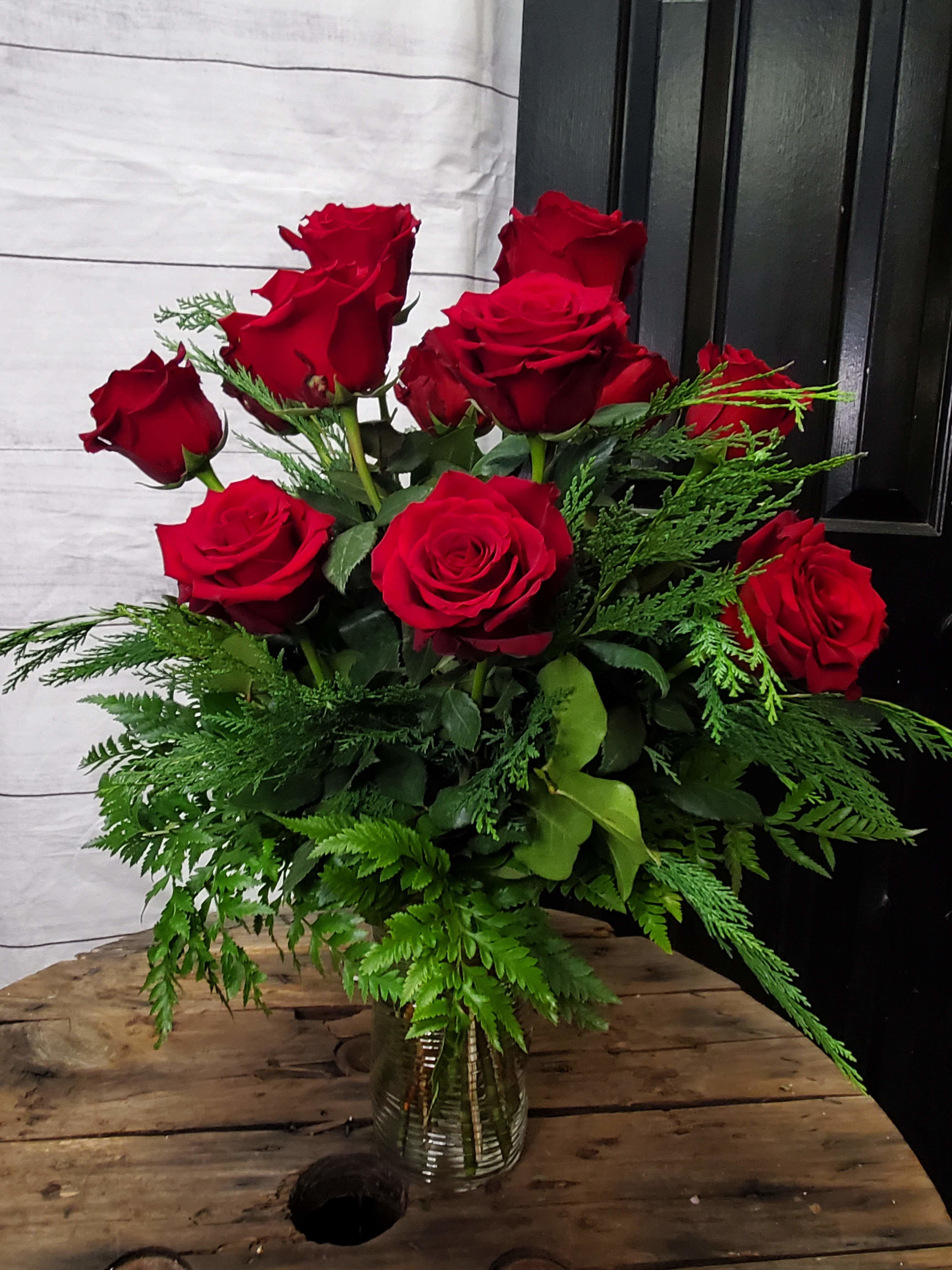 Bouquet of red roses in a clear glass vase with greenery