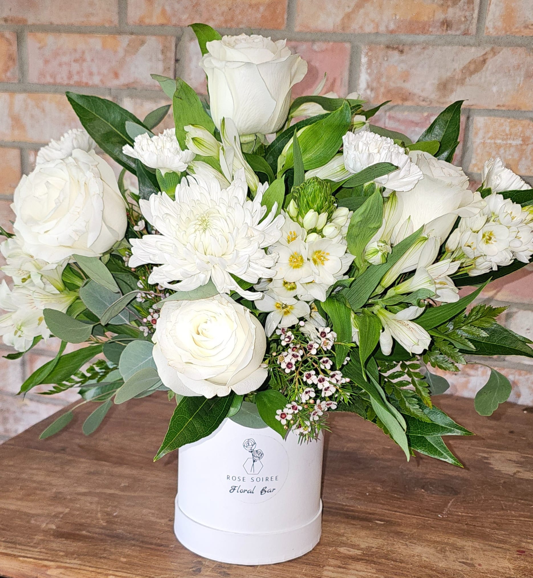 Light of my life Signature Box - The Light of My Life Signature Box features a lush arrangement of fresh blooms in shades of white, ivory, and cream, thoughtfully designed in our signature hatbox for a clean, elevated presentation.  This arrangement is intentionally neutral and timeless, making it a meaningful choice for both life’s more delicate moments and its most thoughtful gestures. Whether you’re offering sympathy, sending comfort, or simply choosing something elegant and understated, this design speaks with quiet intention.  Each piece is created using a curated mix of seasonal florals — which may include roses, spray roses, wax flower, chrysanthemums, and textural accents — ensuring a full, layered design that feels both soft and structured.  Designed to leave a lasting impression without overwhelming the moment, this is one of our most versatile signature arrangements.  Standard Box is approximately 5" x 5.5" Deluxe Box is approximately 6.5" x 6.5" Premium Box is approximately 7.25" x 7.25"
