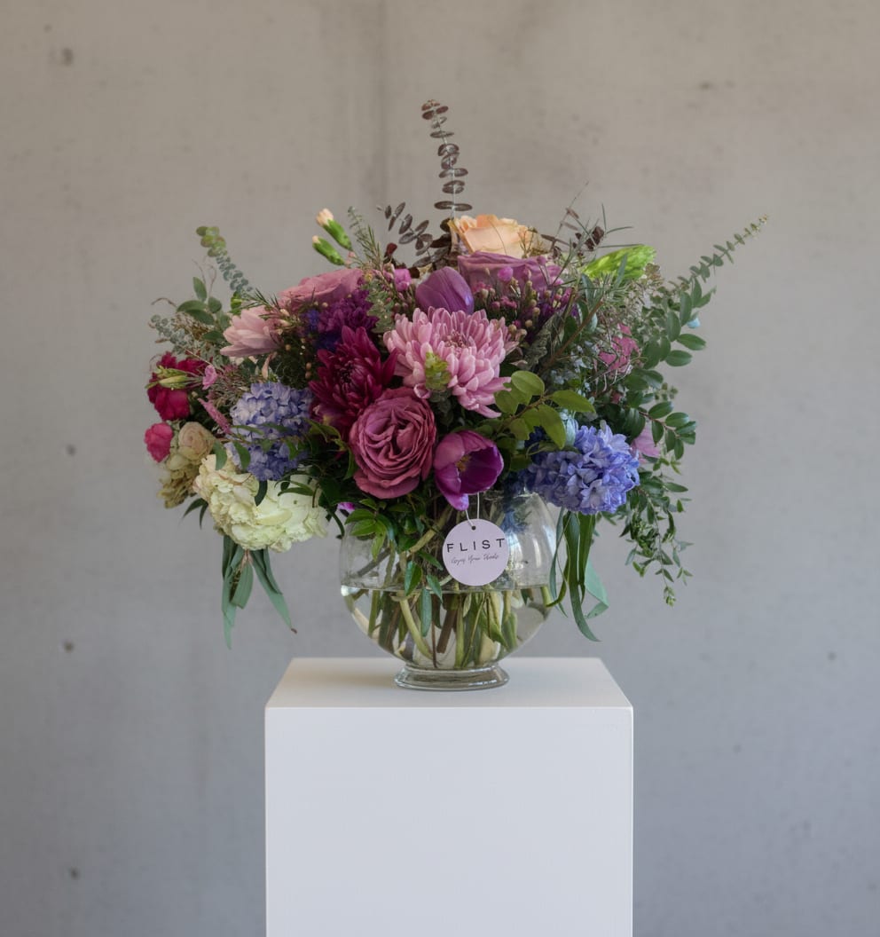 Bellview - Lydia is pretty in purple with a florist choice of seasonal purple and lavender florals in a bowl vase. Arrangements arrives full of purple hues and full of class.