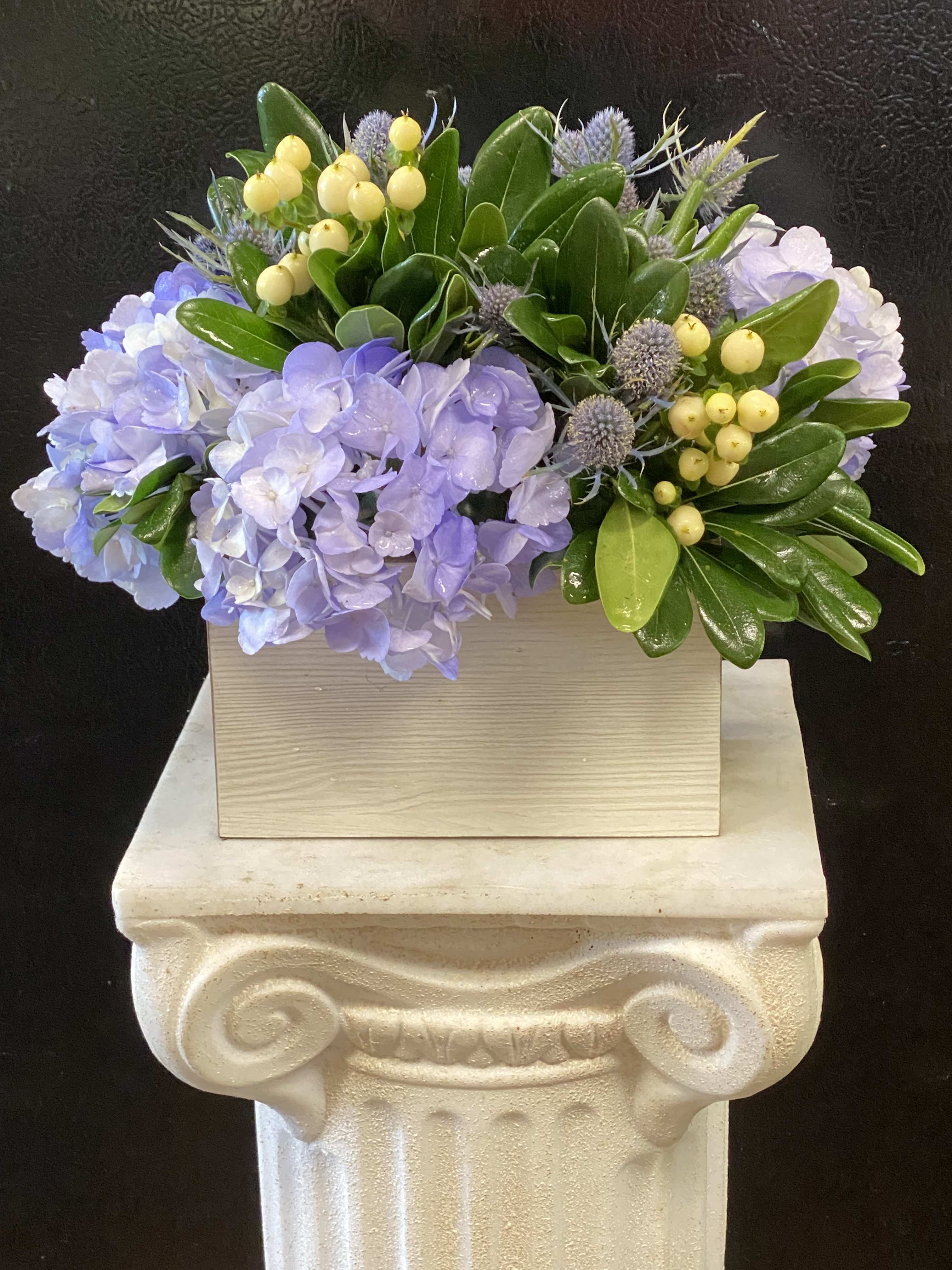 Lavender hydrangeas with yellow berries in a wooden box