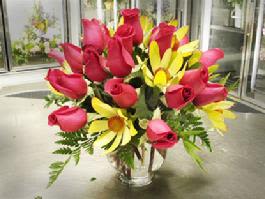 Bouquet of red roses and yellow daisies in a clear vase